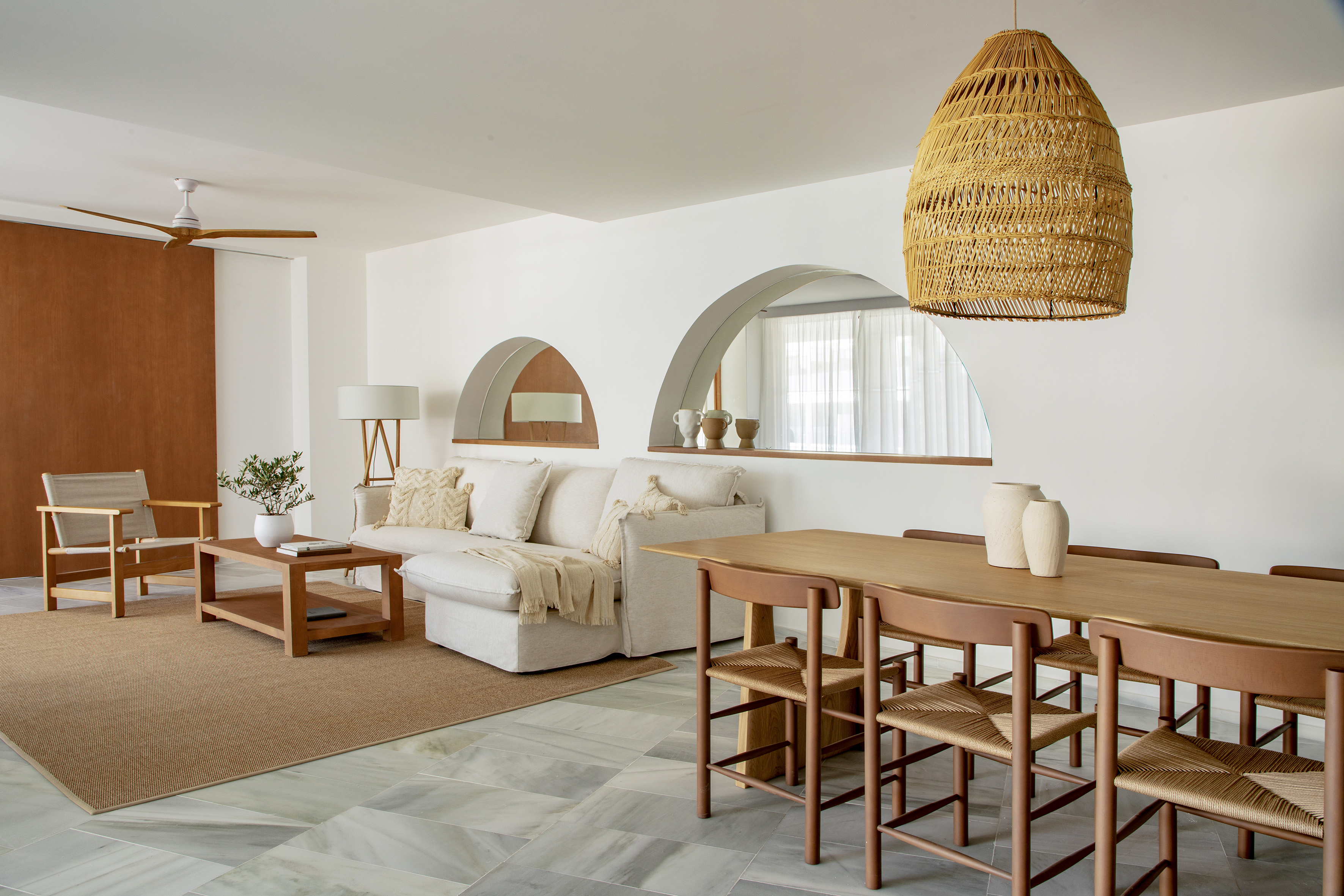 Neutral open-plan living and dining room with wooden furniture and wicker details.