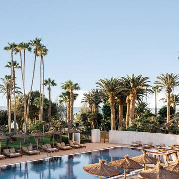 a pool with lounge chairs and umbrellas and palm trees
