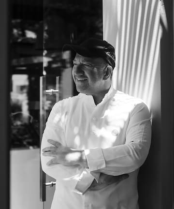 a man in a hat leaning against a wall