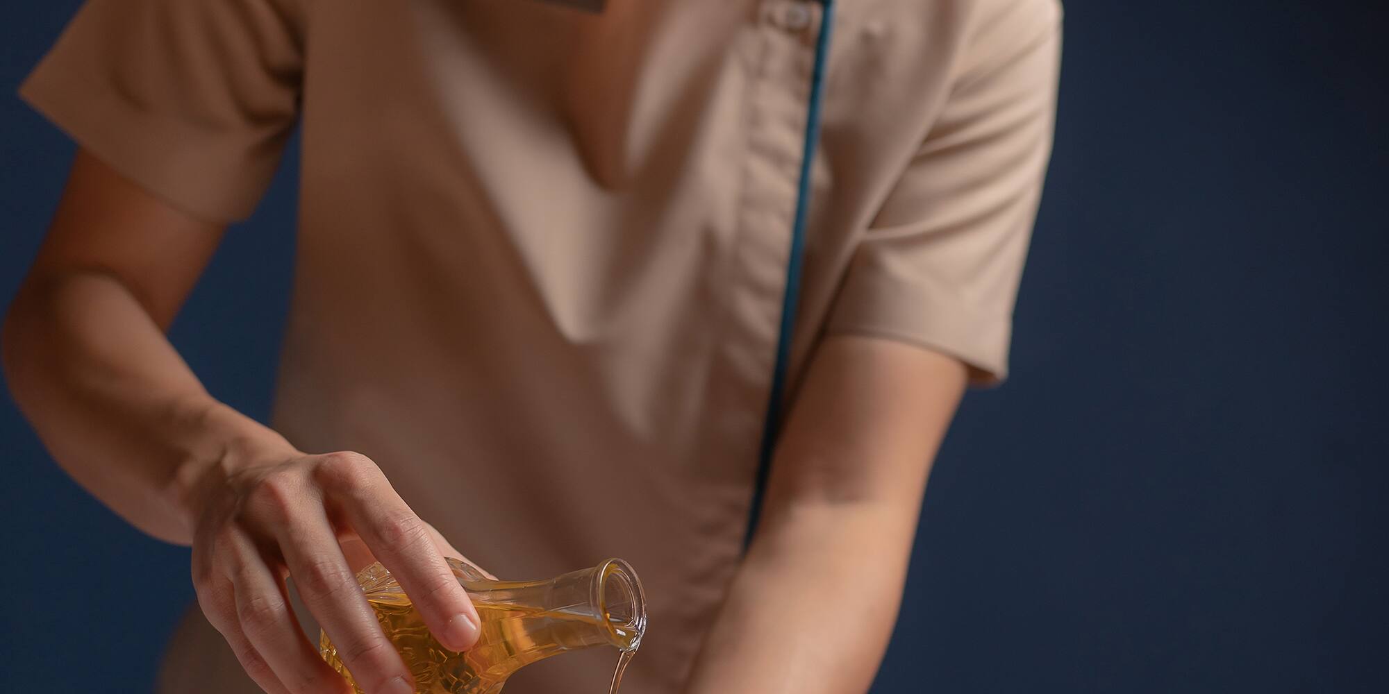a woman pouring oil onto a woman's back