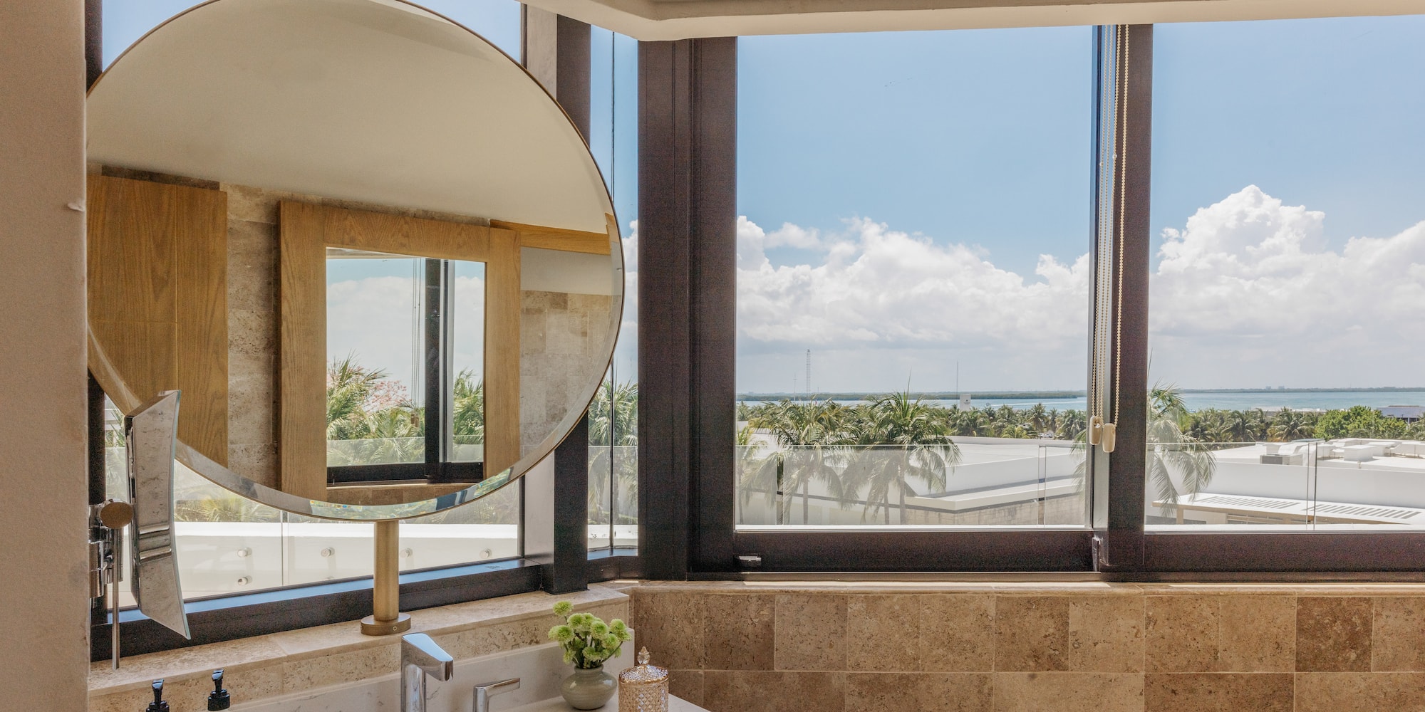 Modern bathroom vanity, round mirror, large window with ocean view.