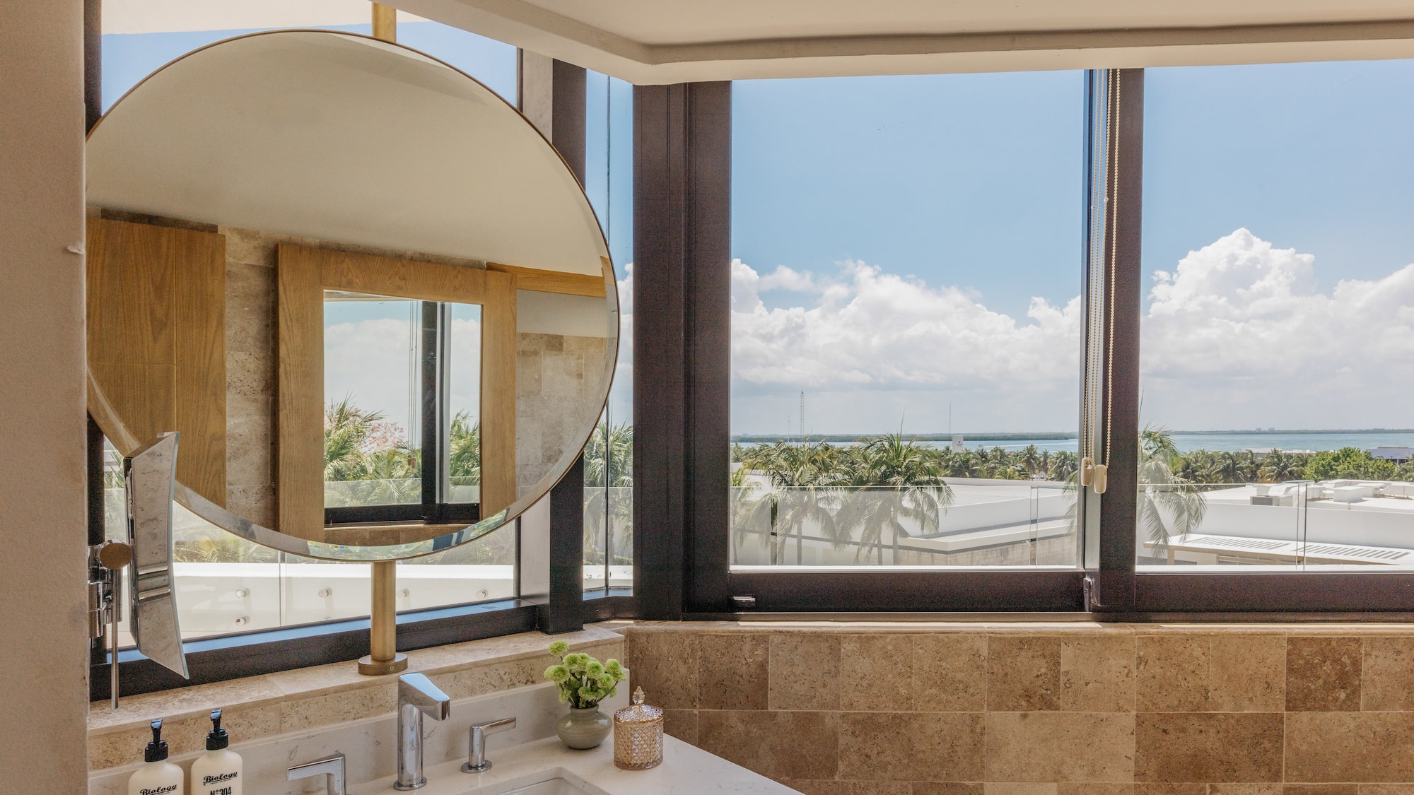 Modern bathroom vanity, round mirror, large window with ocean view.