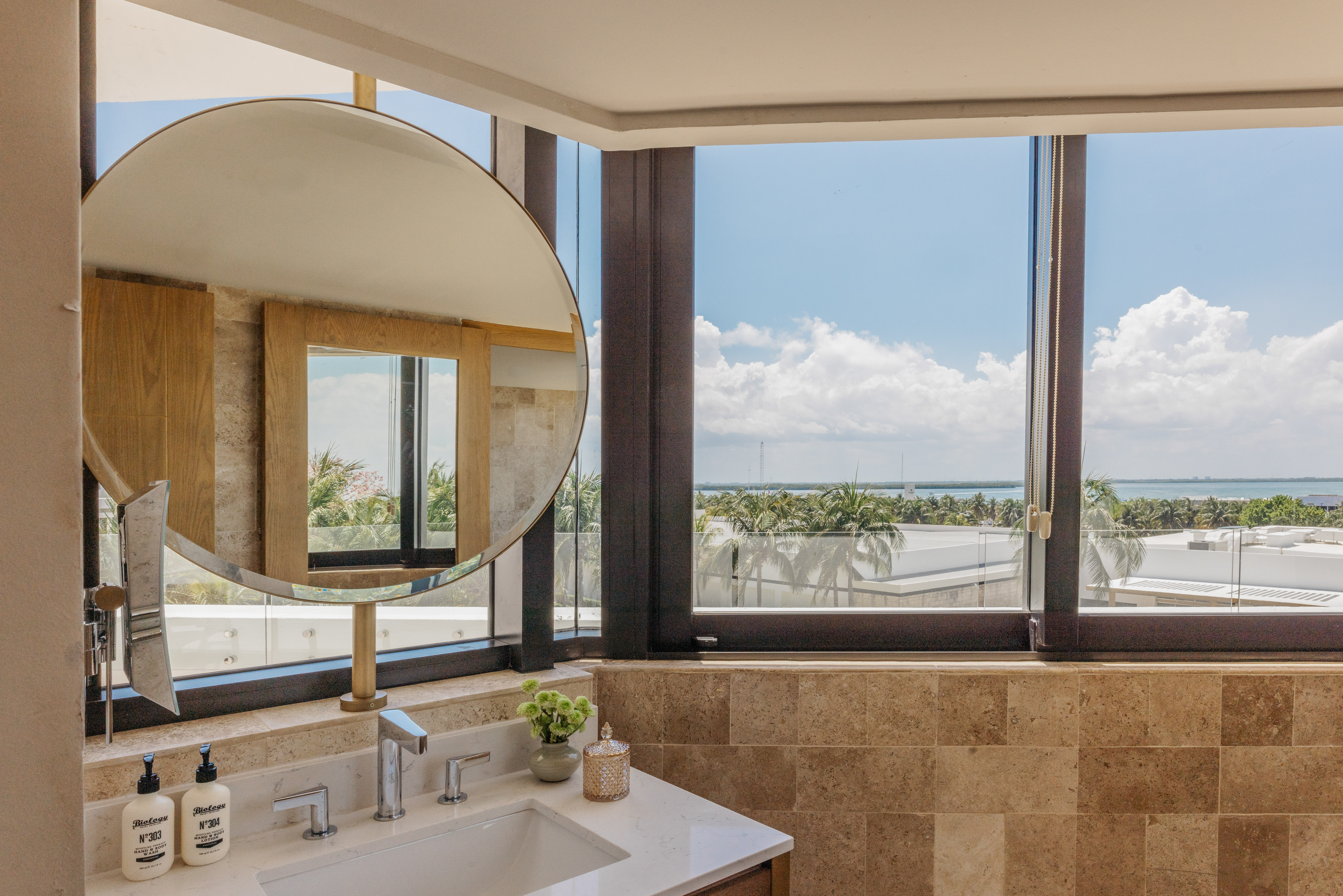 Modern bathroom vanity, round mirror, large window with ocean view.