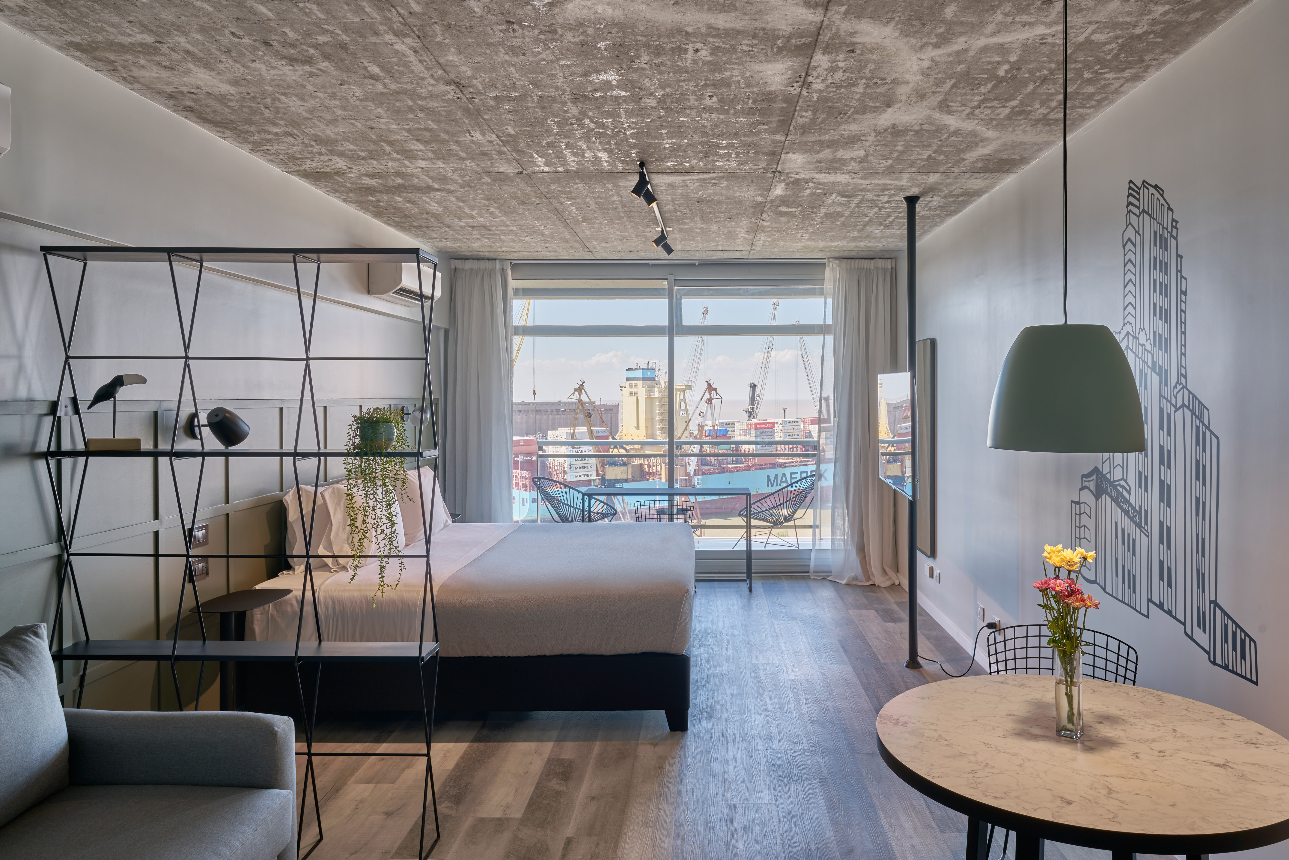 Modern industrial studio with port view, concrete ceiling, and bedroom.
