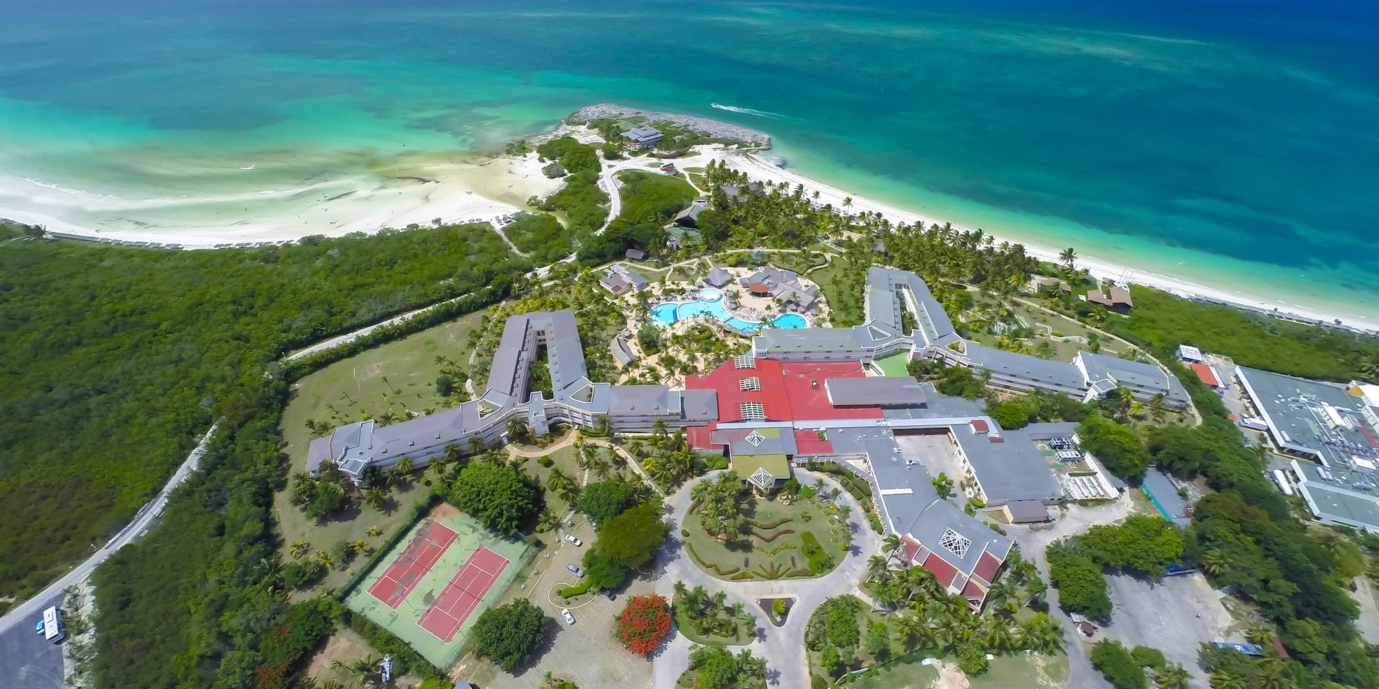 an aerial view of a resort with a beach and trees