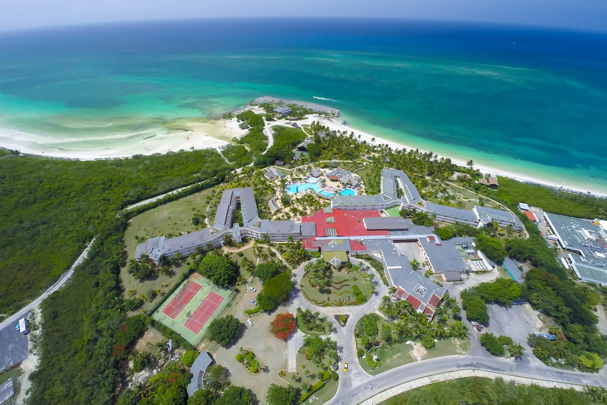an aerial view of a resort with a beach and trees