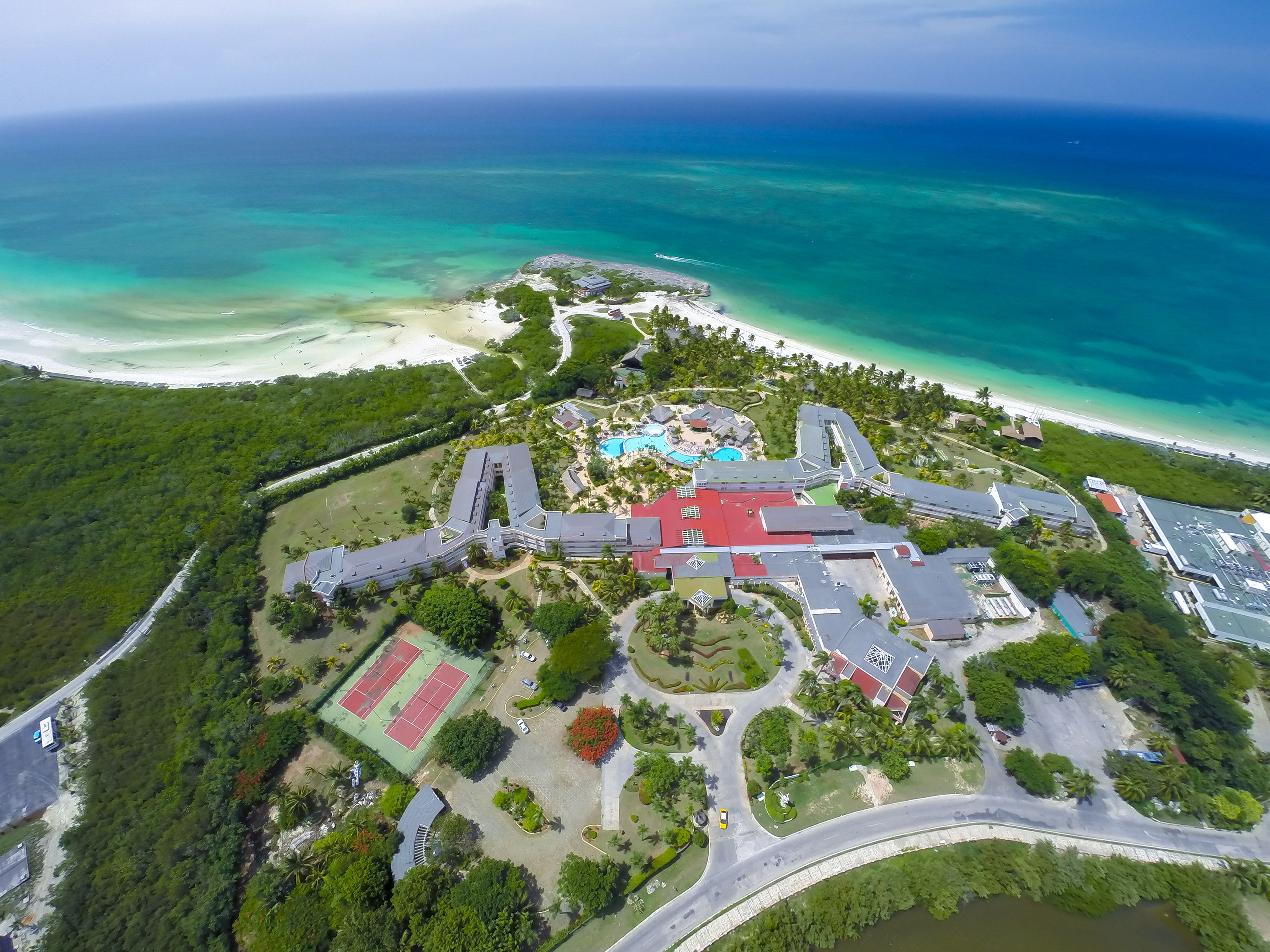an aerial view of a resort with a beach and trees
