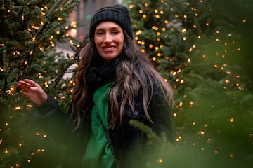a woman standing in front of christmas trees