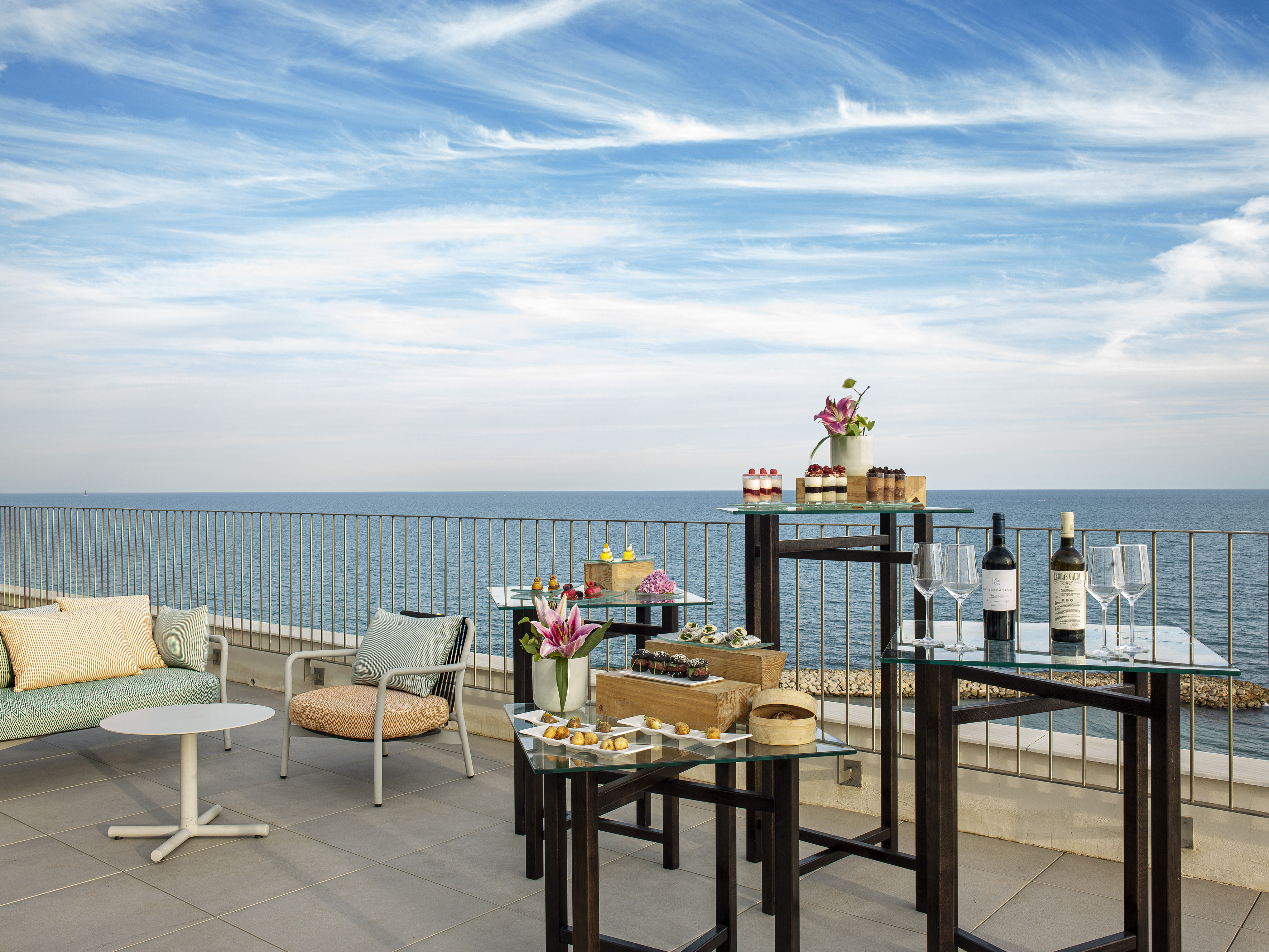 Oceanfront terrace with appetizers, desserts, wine, and lounge seating.
