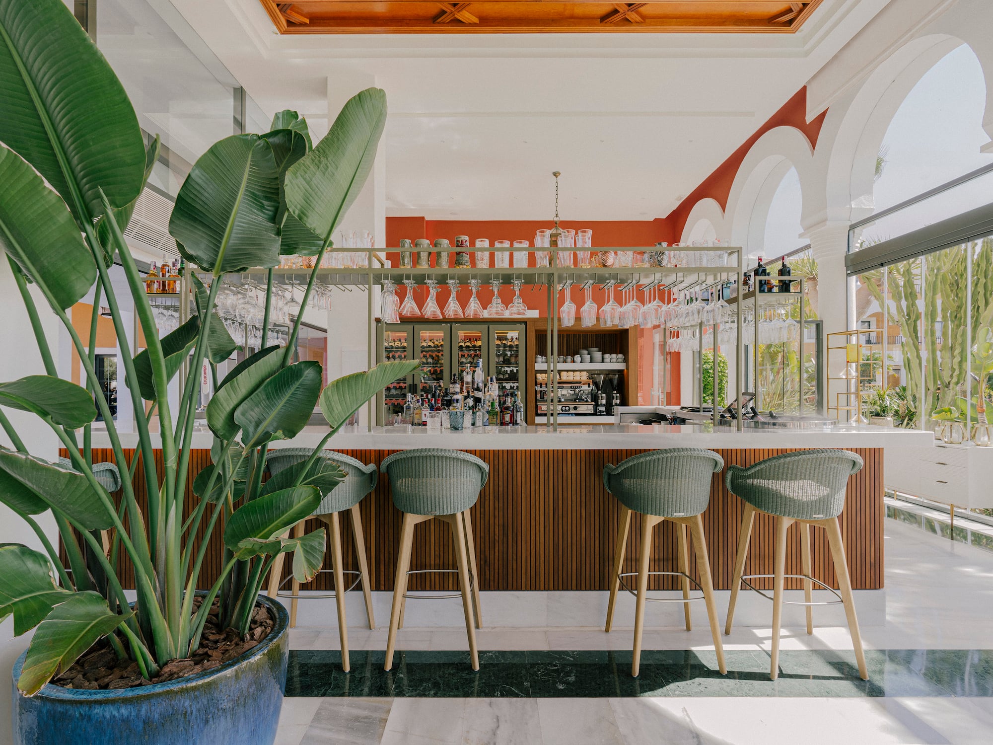 a bar with chairs and plants in a room