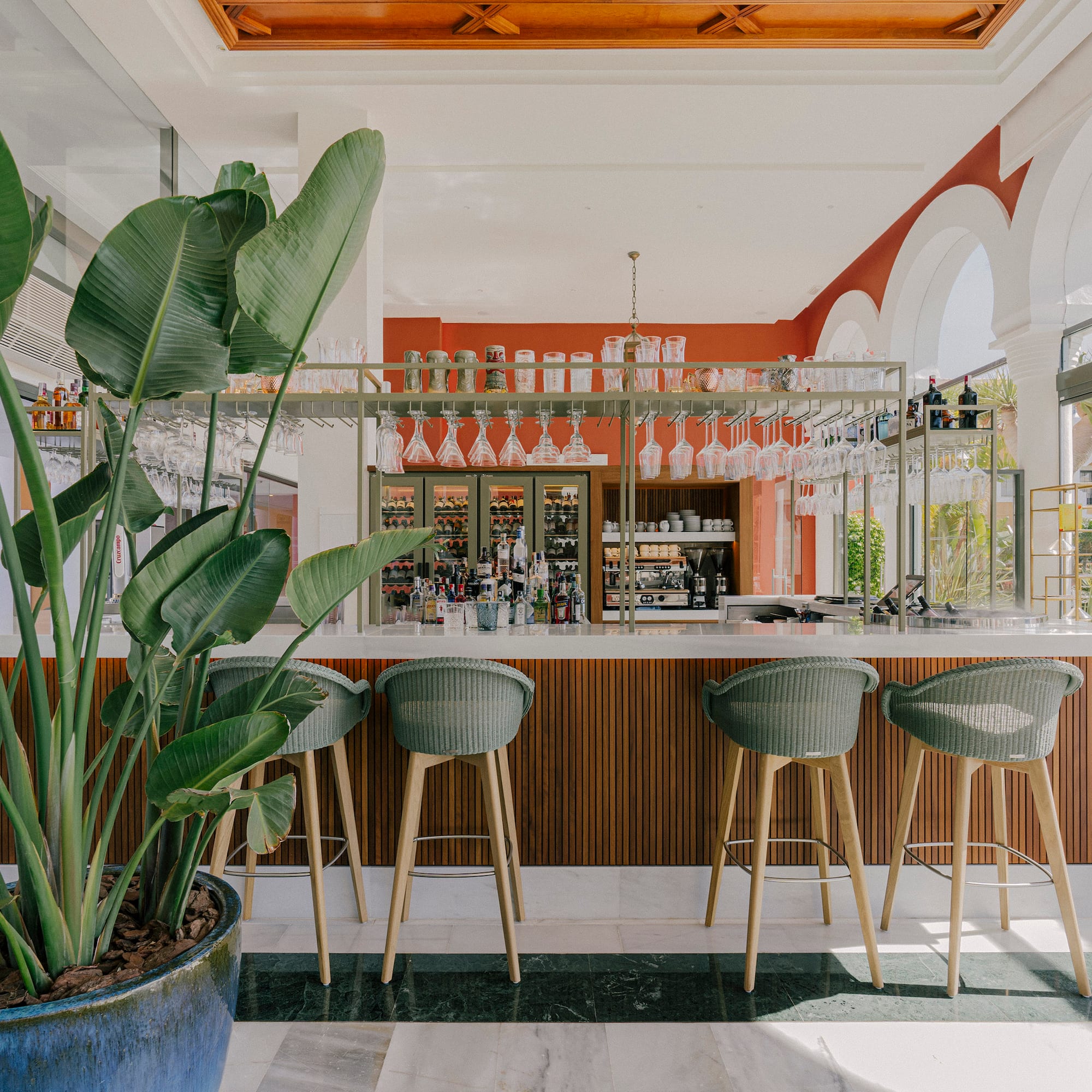 a bar with chairs and plants in a room