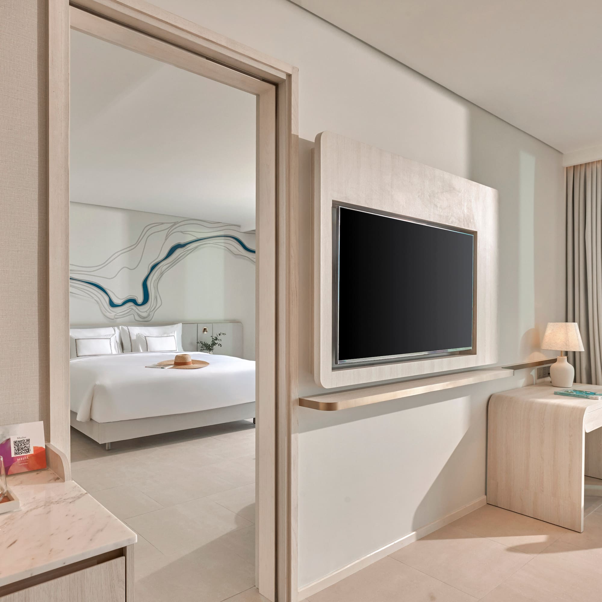 Modern hotel room with bedroom, wall TV, desk, and mountain view.