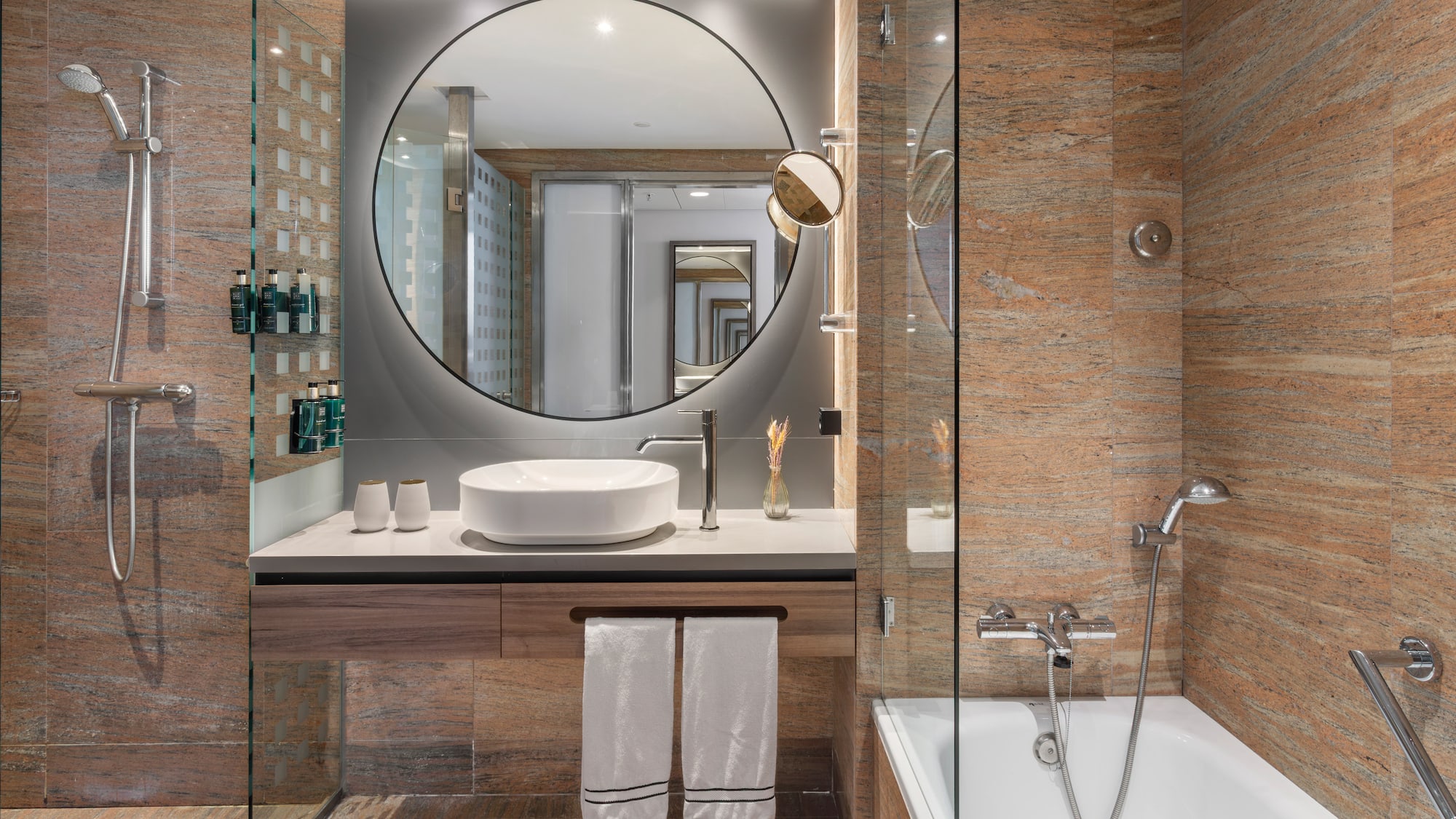 Baño moderno hotel. Ducha, bañera, lavabo, espejo y paredes de granito.