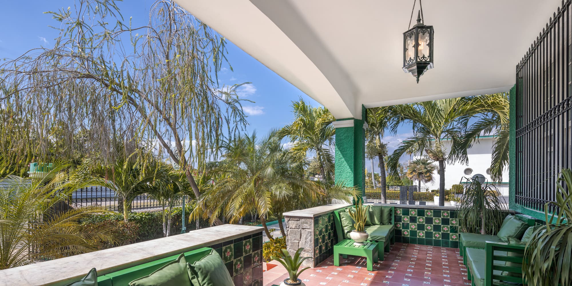 a green and white patio with green chairs and a lamp