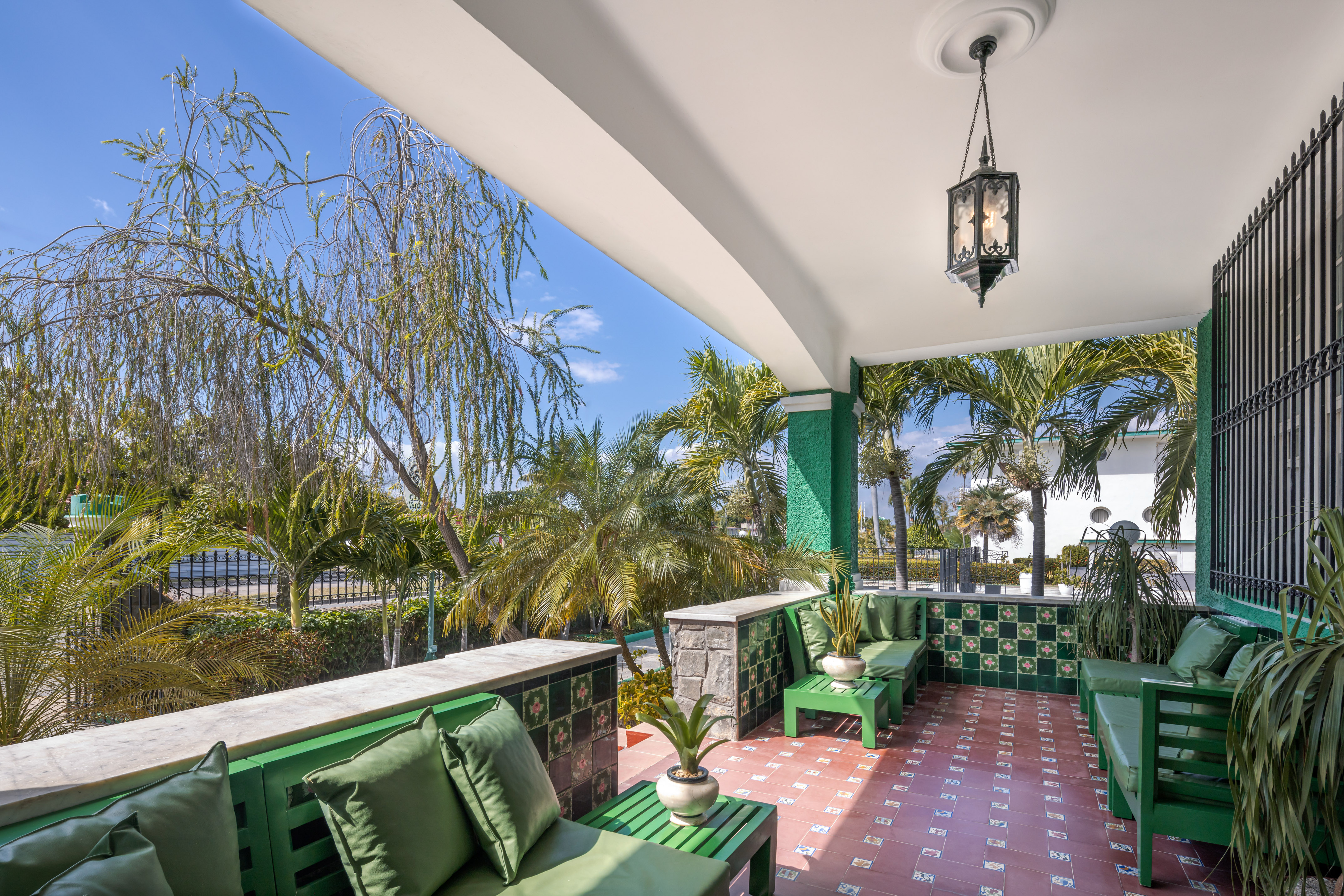a green and white patio with green chairs and a lamp
