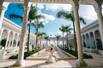 a woman in white dress posing for a picture under a fountain