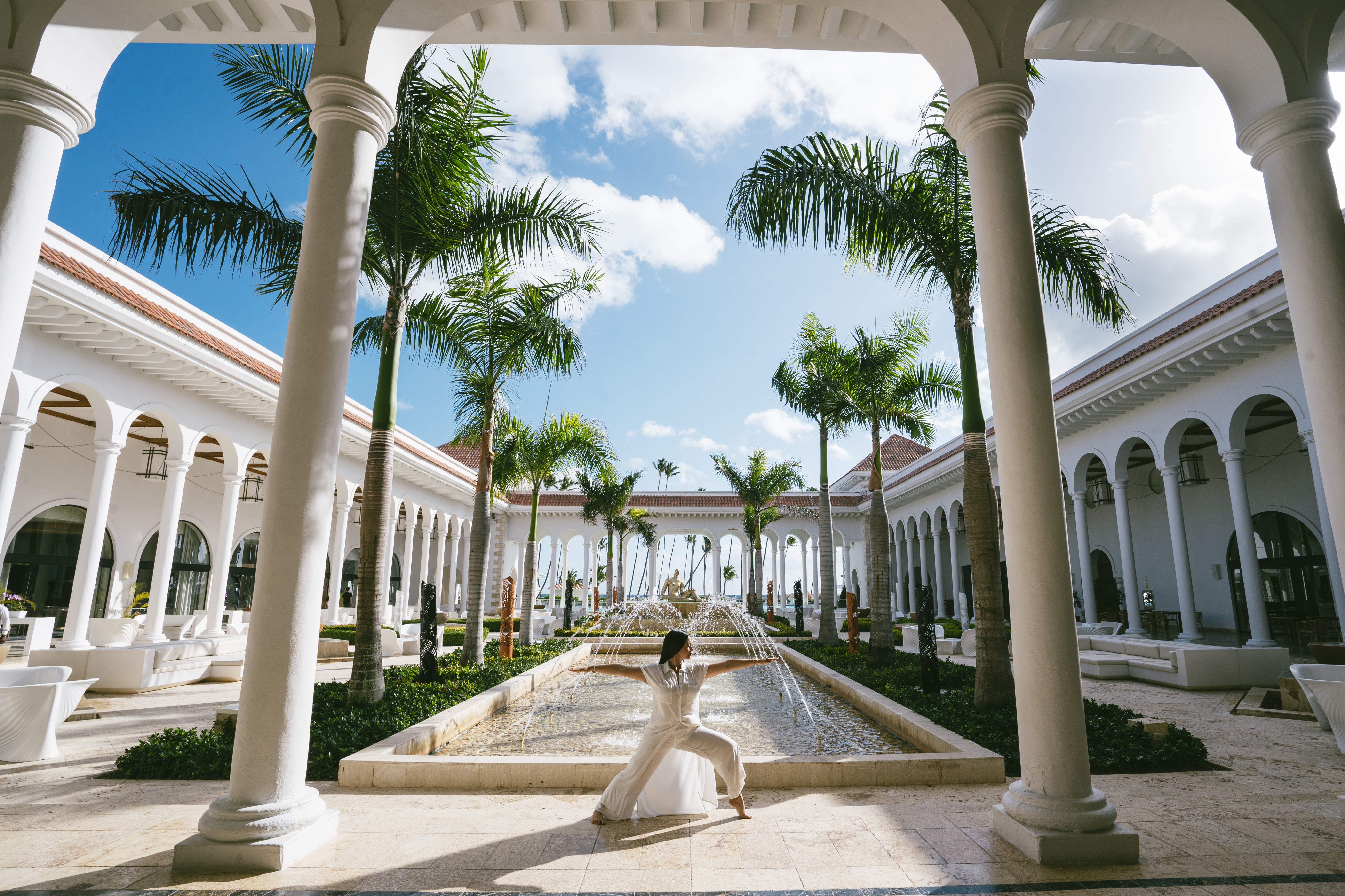 a woman in white dress posing for a picture under a fountain