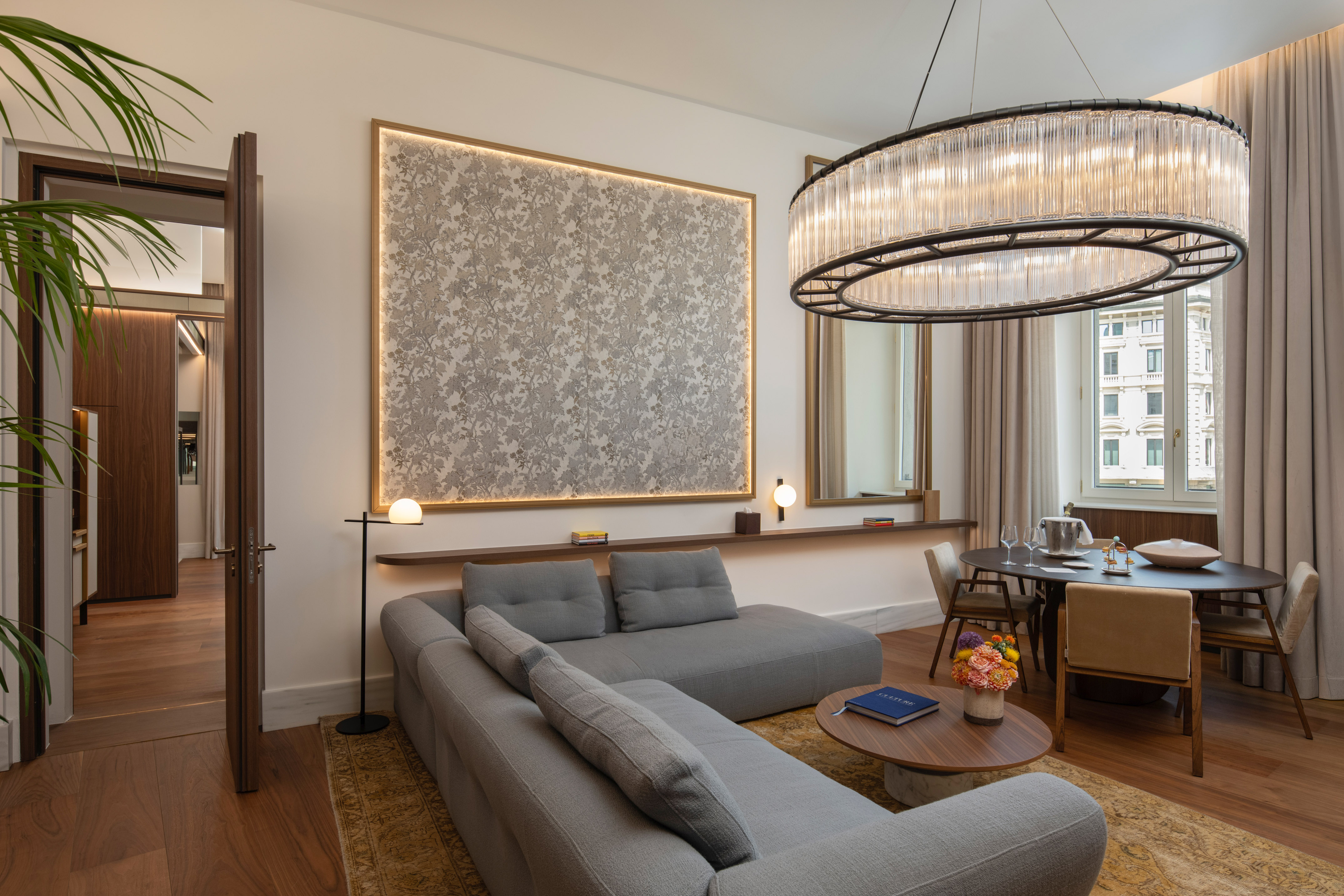 Modern luxury living room with grey sofa, dining table, and stunning chandelier.
