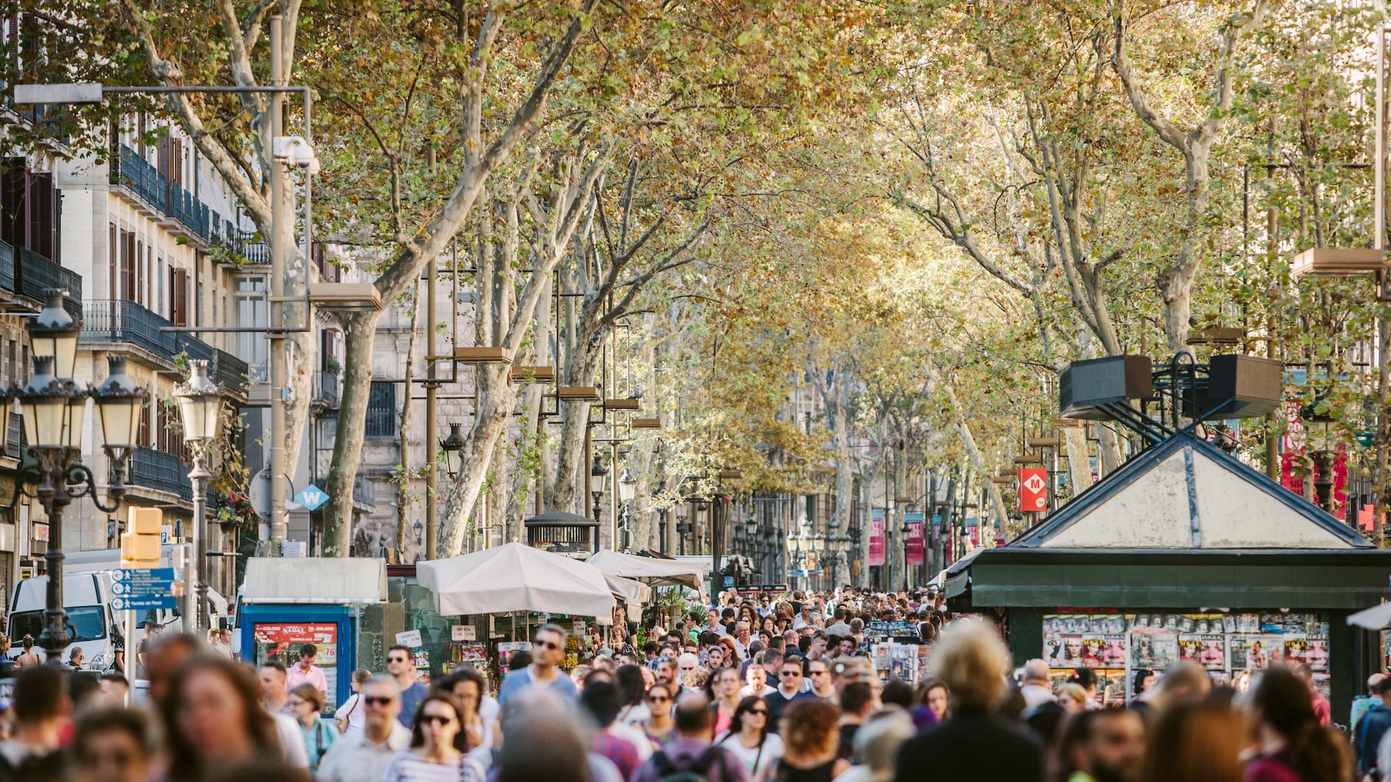 a crowd of people walking down a street with La Rambla, Barcelona in the background