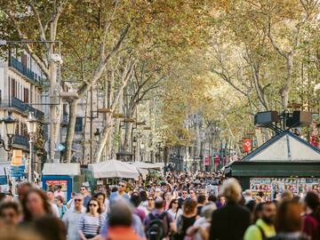 a crowd of people walking down a street with La Rambla, Barcelona in the background