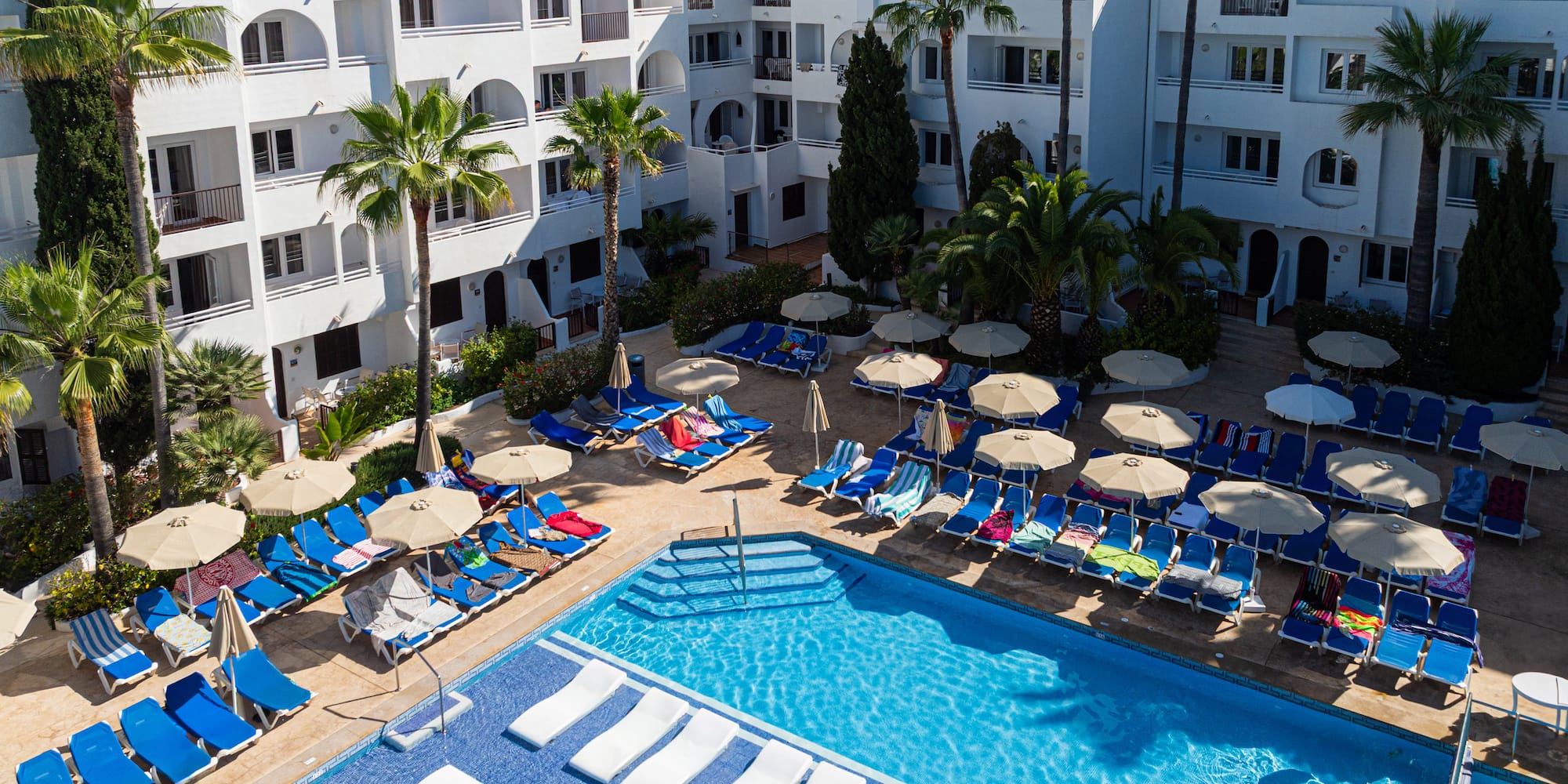 a pool with lounge chairs and umbrellas in front of a building
