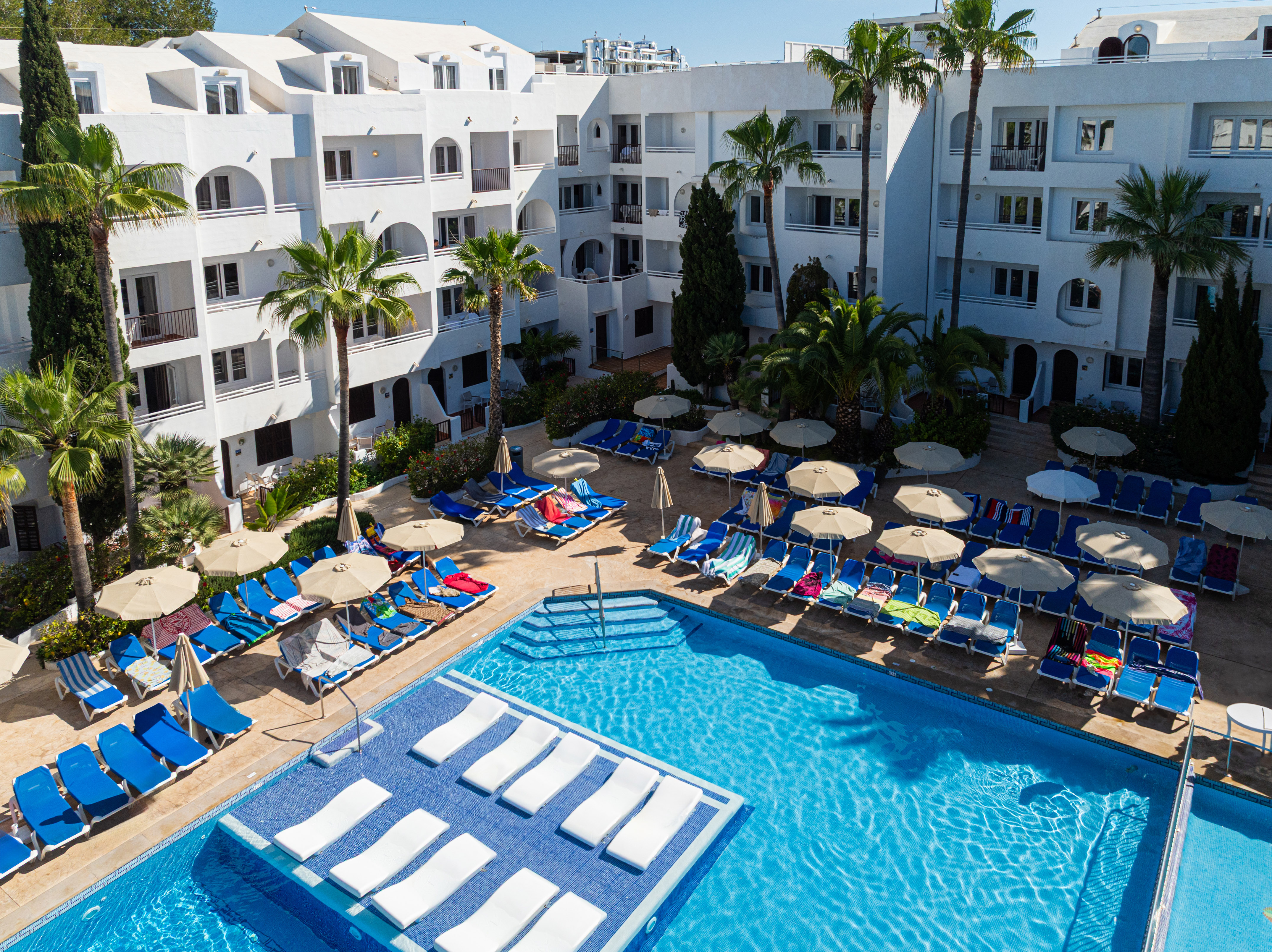 a pool with lounge chairs and umbrellas in front of a building