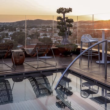 a pool with chairs and a view of a city