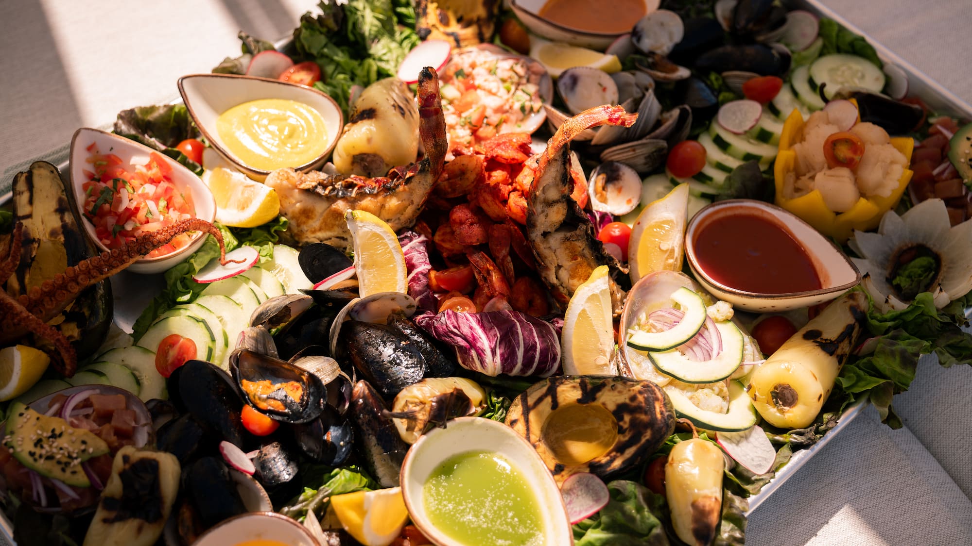 a plate of seafood with sauces and vegetables