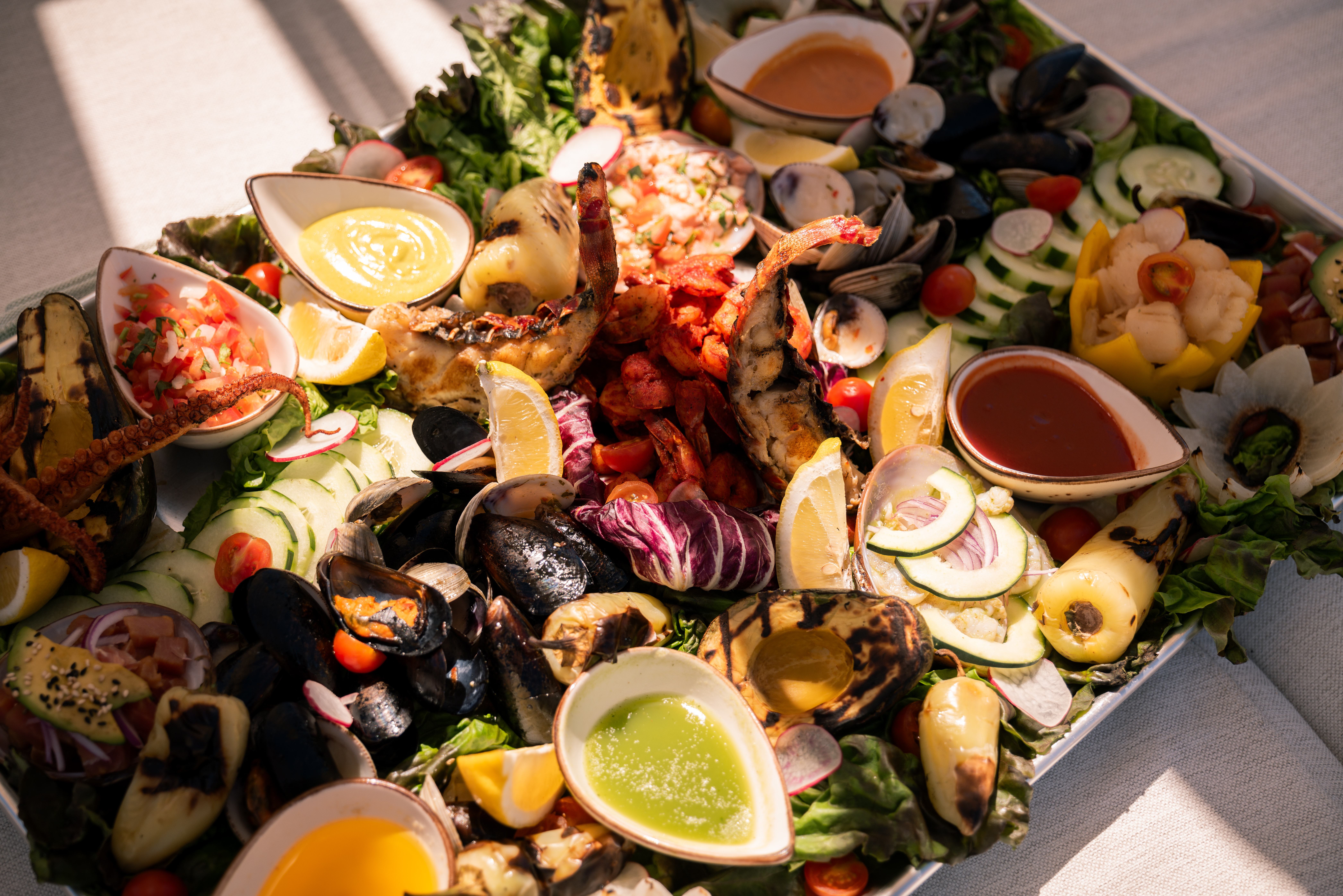 a plate of seafood with sauces and vegetables