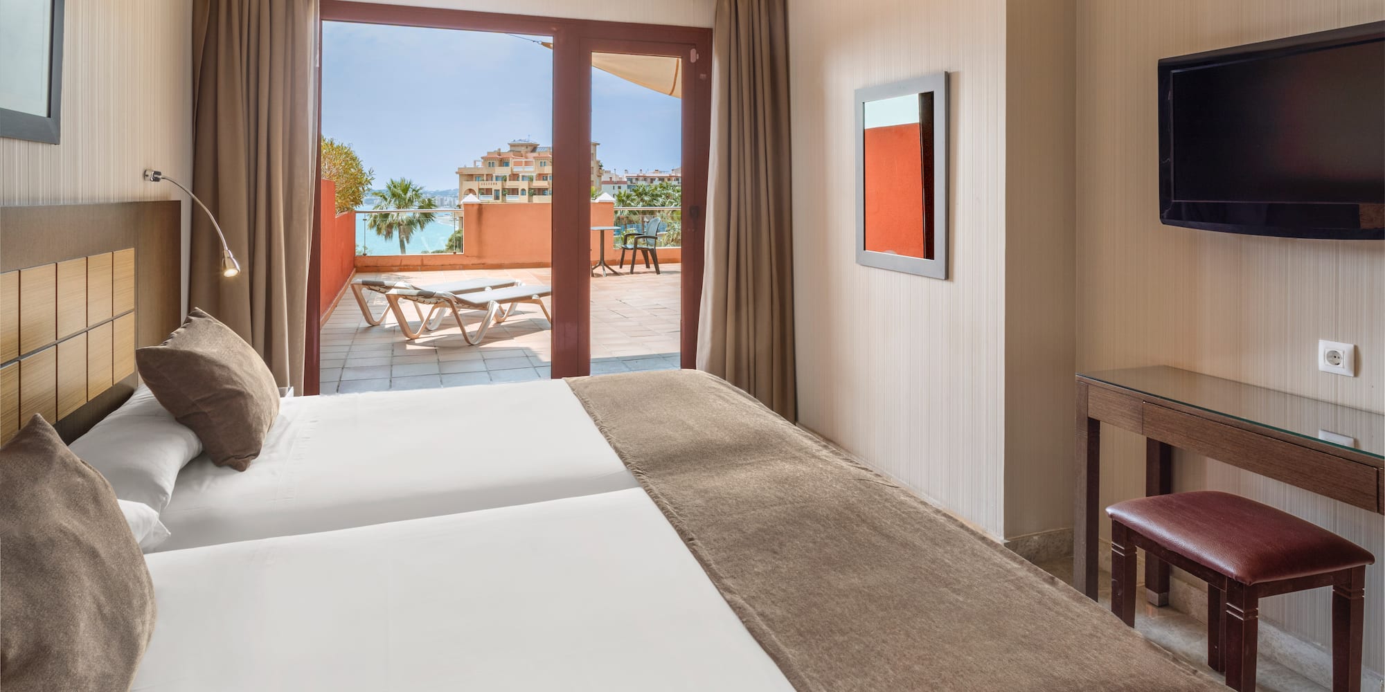 Resort hotel room with twin beds, private balcony, and ocean view.