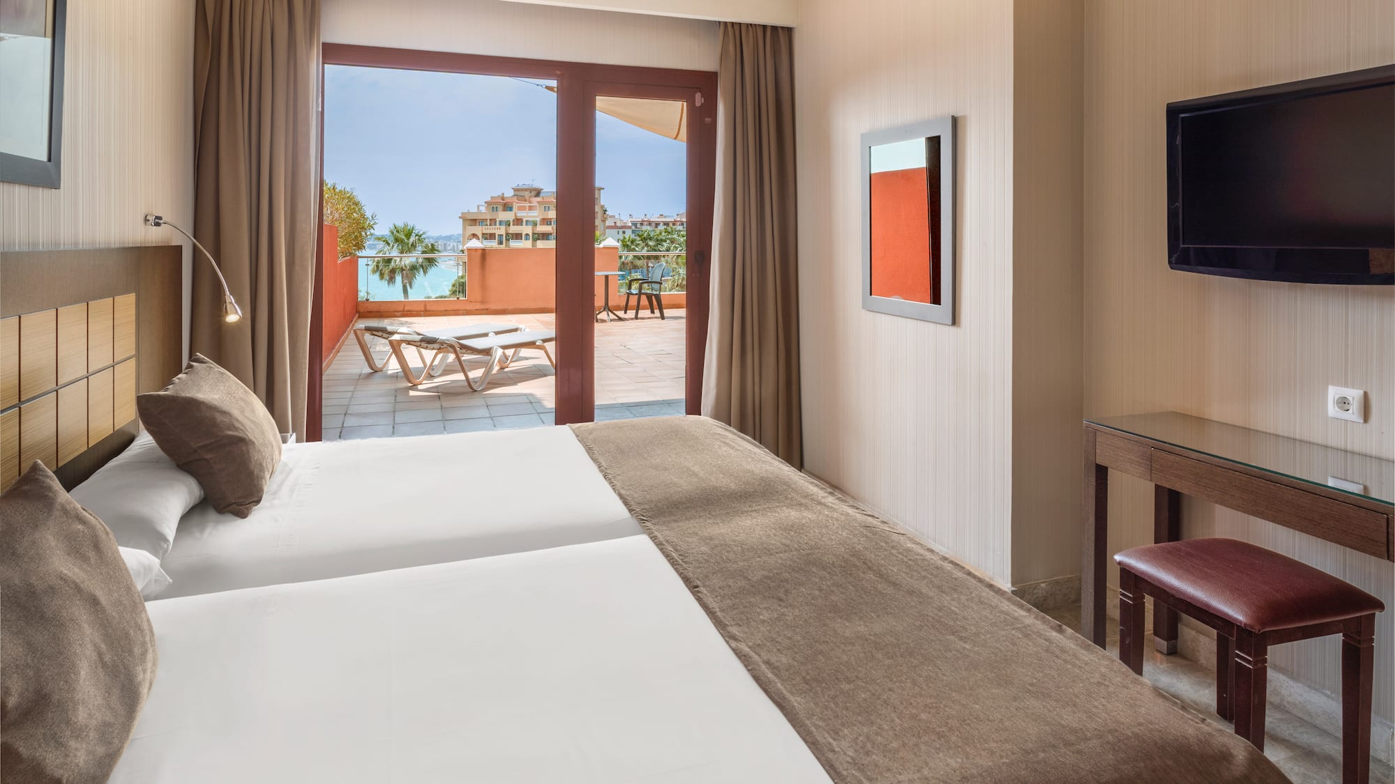 Resort hotel room with twin beds, private balcony, and ocean view.