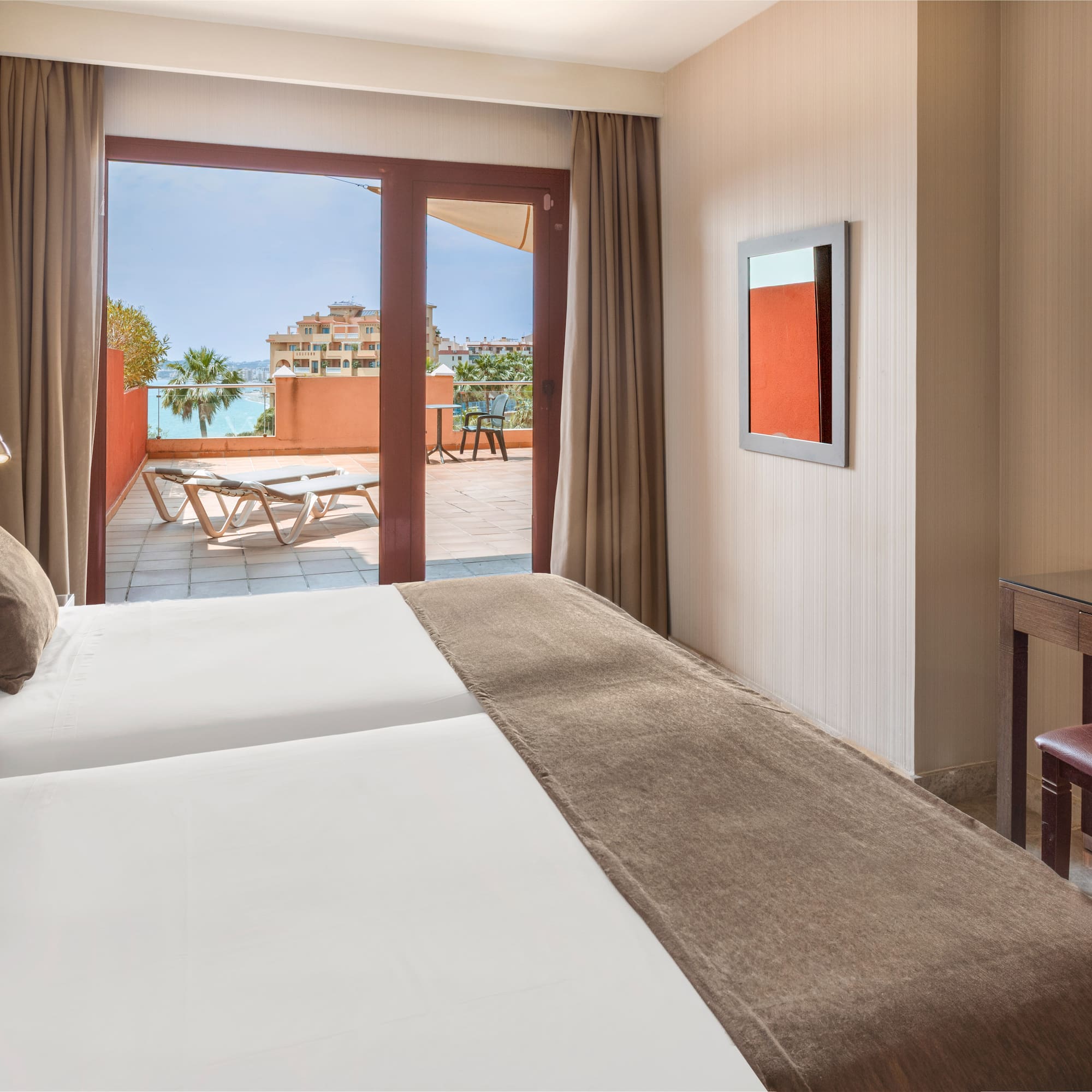 Resort hotel room with twin beds, private balcony, and ocean view.