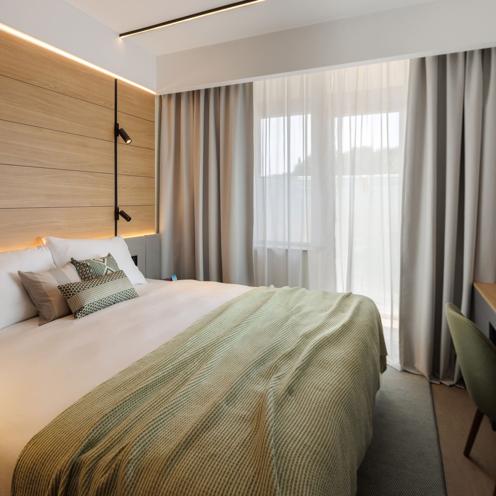 a bed with a green blanket and a wood paneled wall