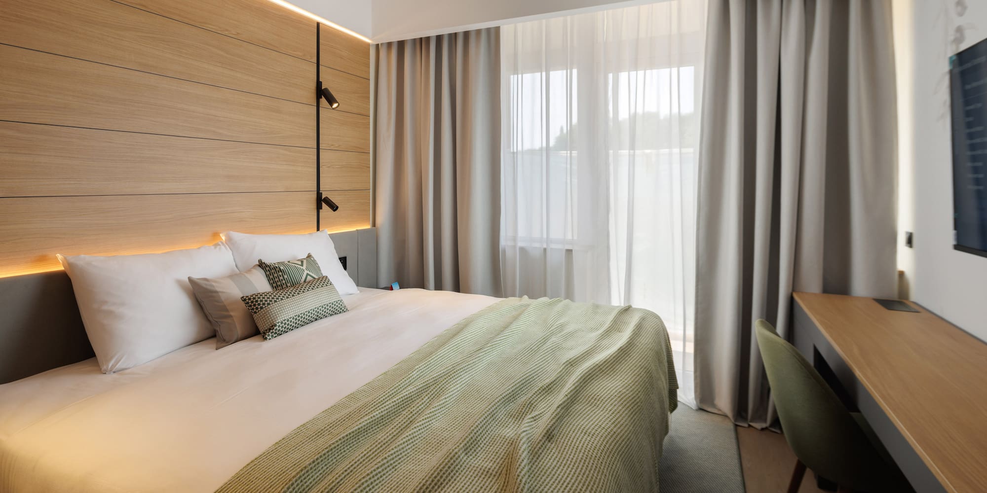 a bed with a green blanket and a wood paneled wall