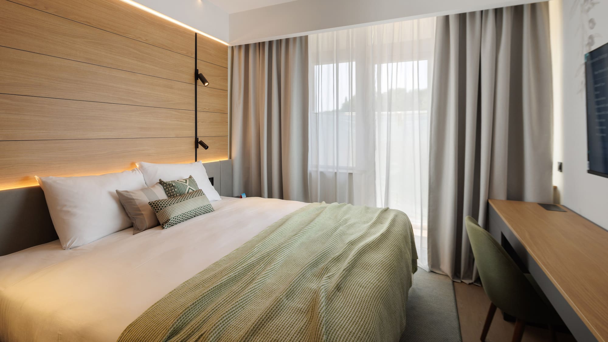 a bed with a green blanket and a wood paneled wall