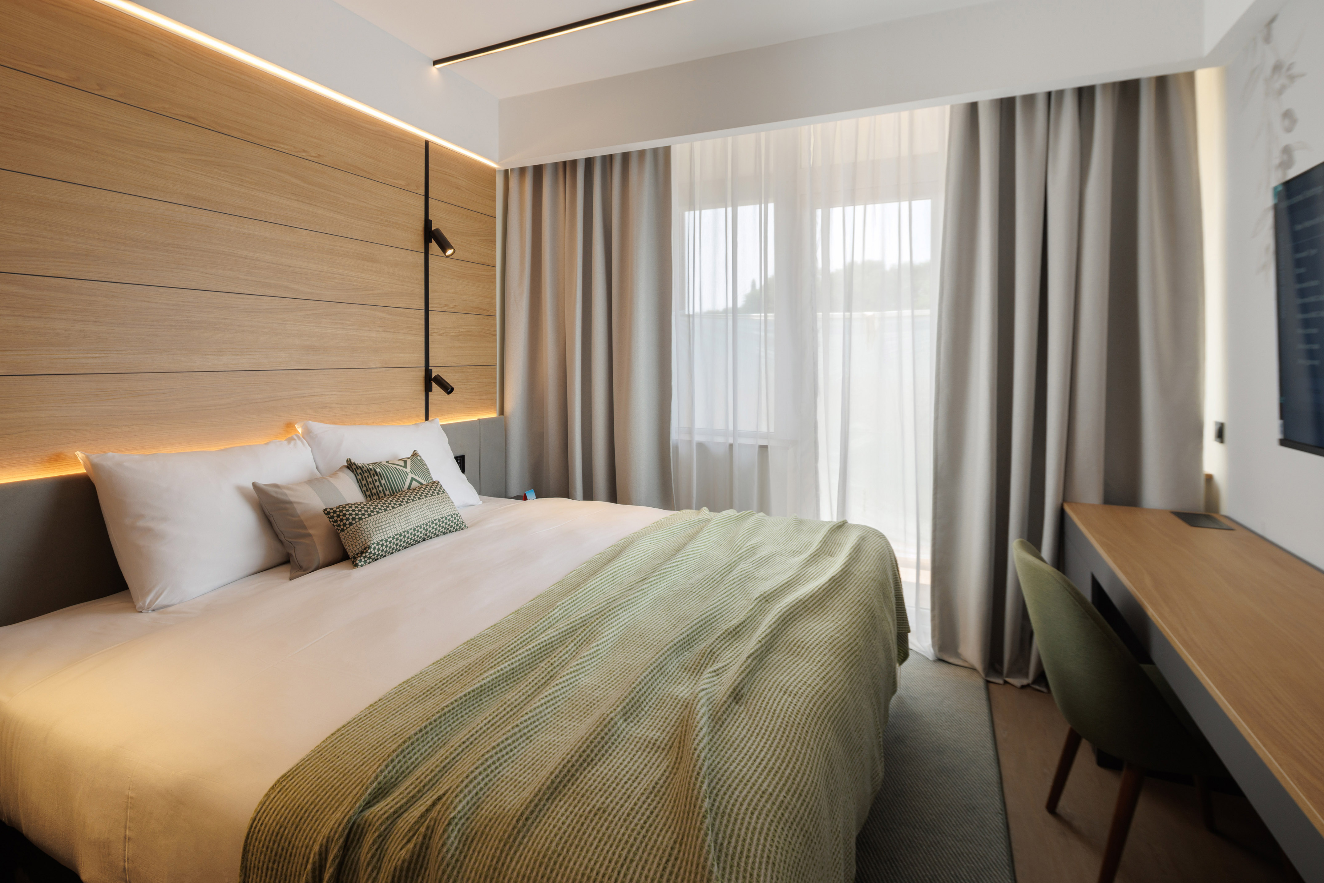 a bed with a green blanket and a wood paneled wall