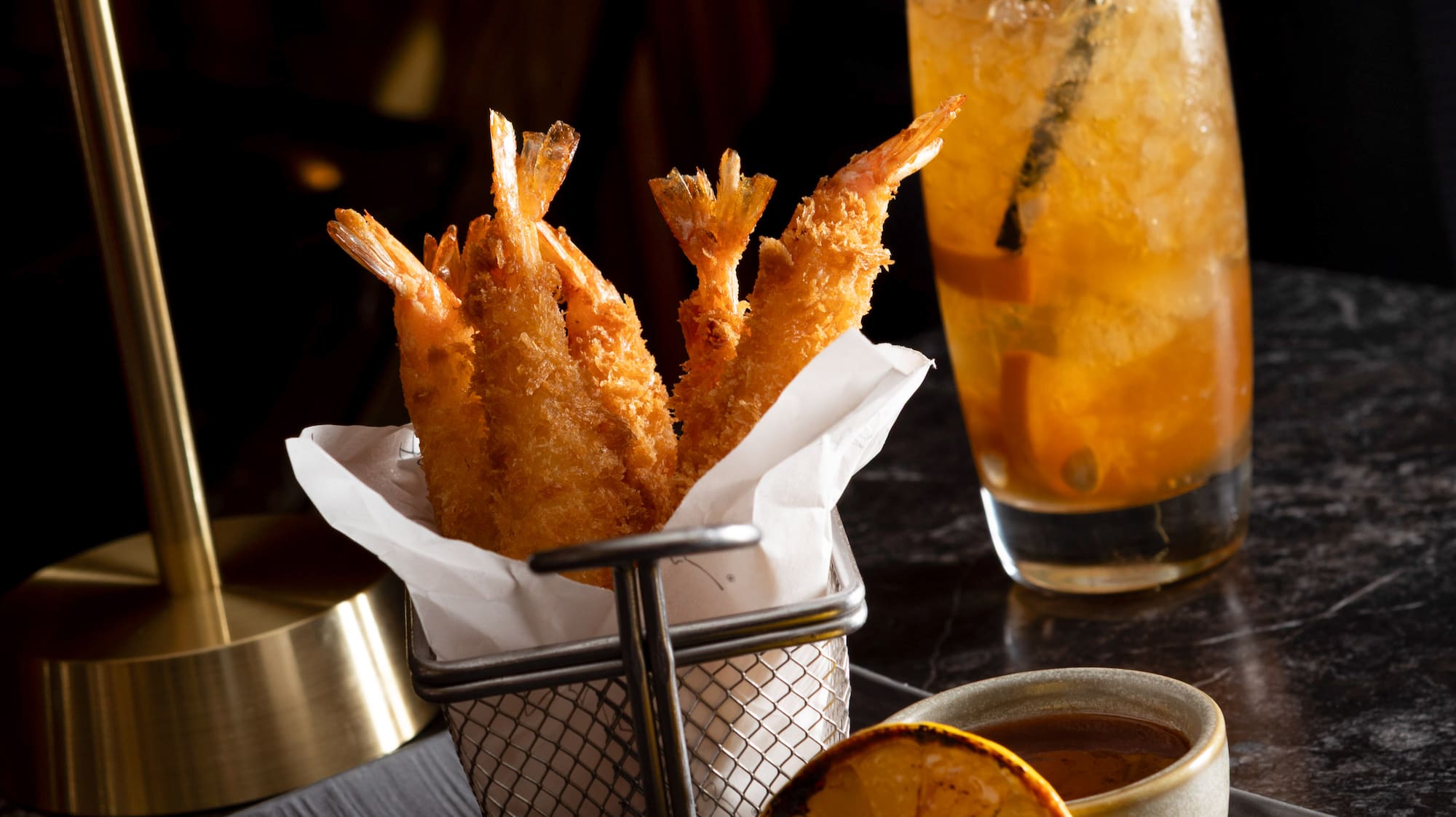 a plate of fried shrimp and a lemon on a black surface