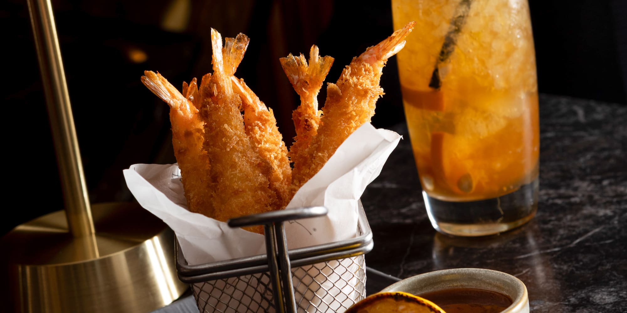 a plate of fried shrimp and a lemon on a black surface