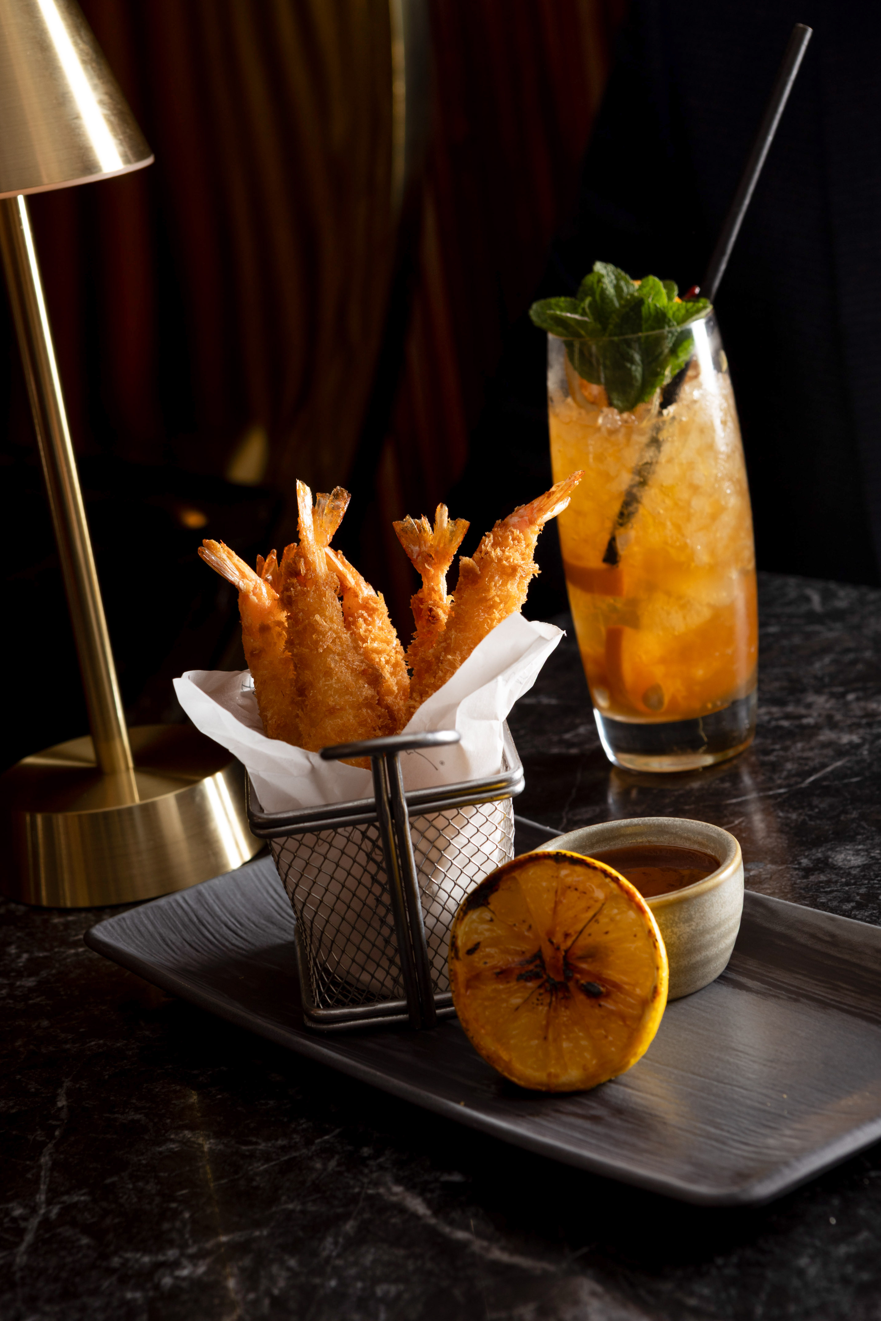 Crispy fried shrimp, grilled lemon, sauce, and an iced cocktail.