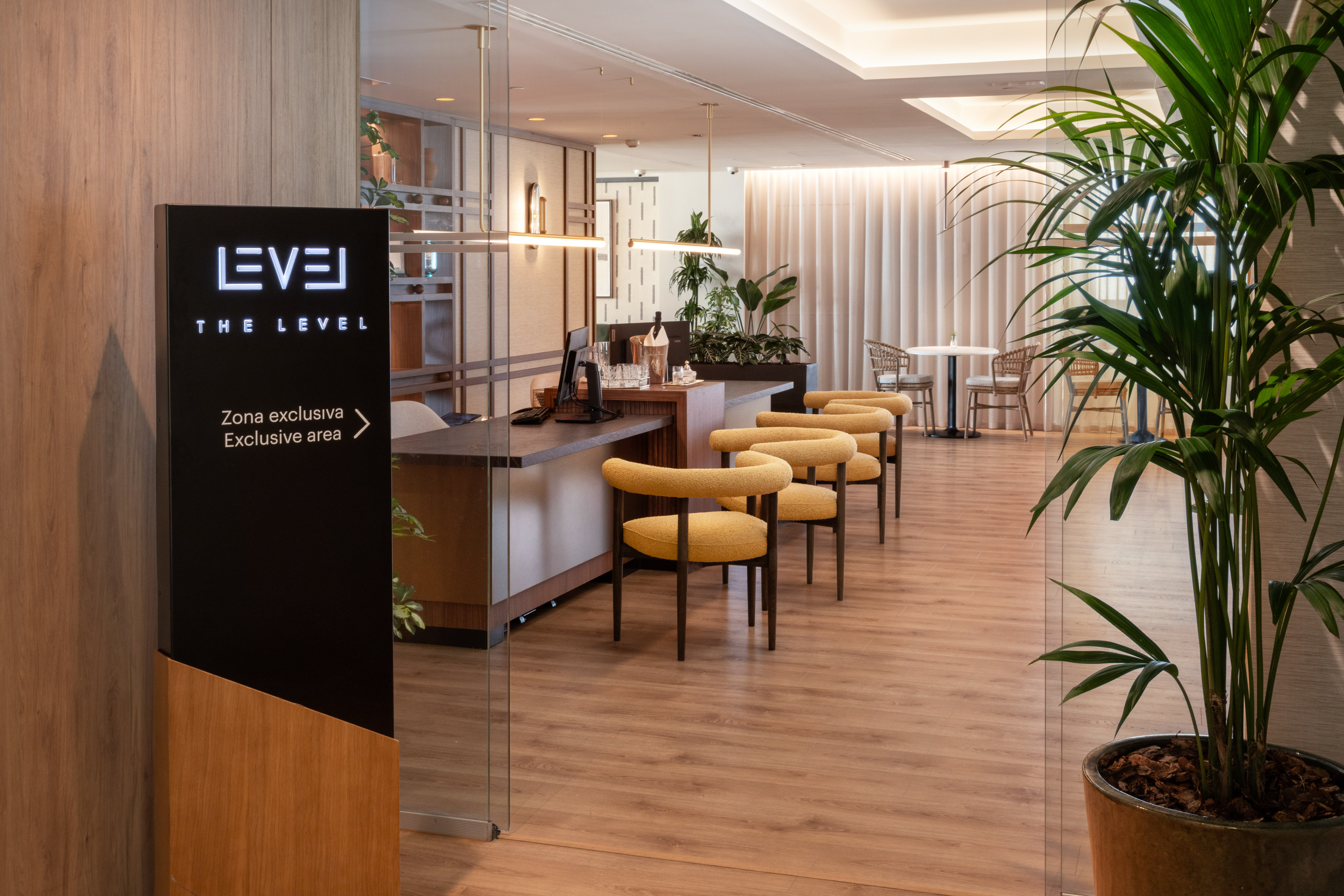 The Level exclusive area, modern reception desk, yellow chairs, wood floor.