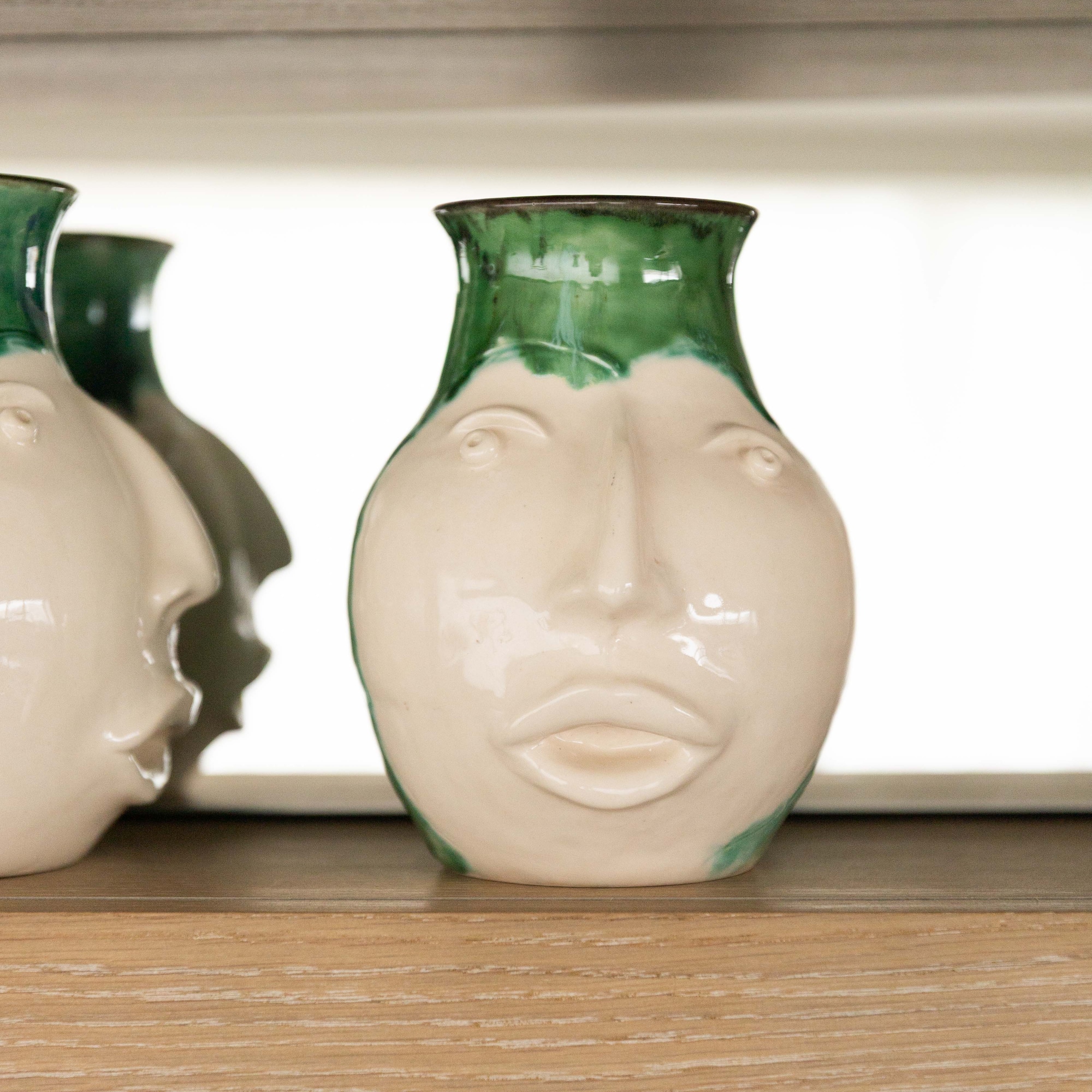 a white and green vases on a shelf