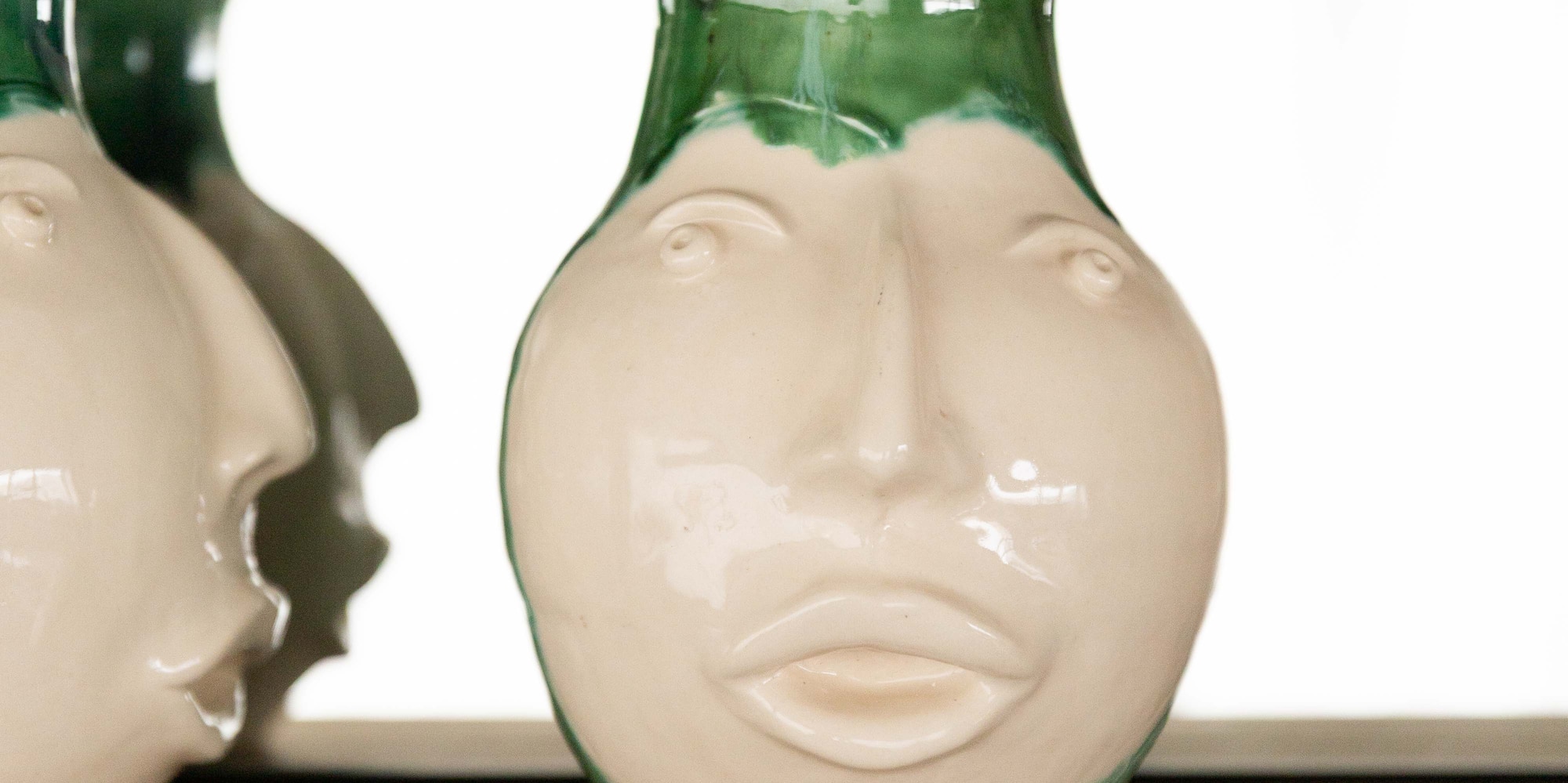 a white and green vases on a shelf