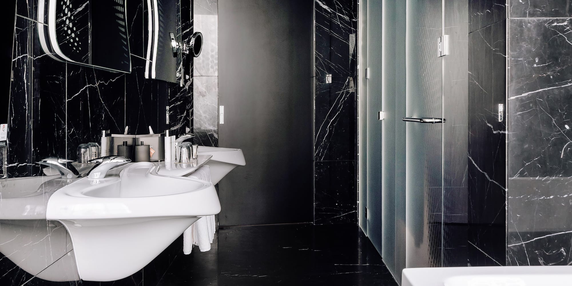 a bathroom with black marble walls and sinks