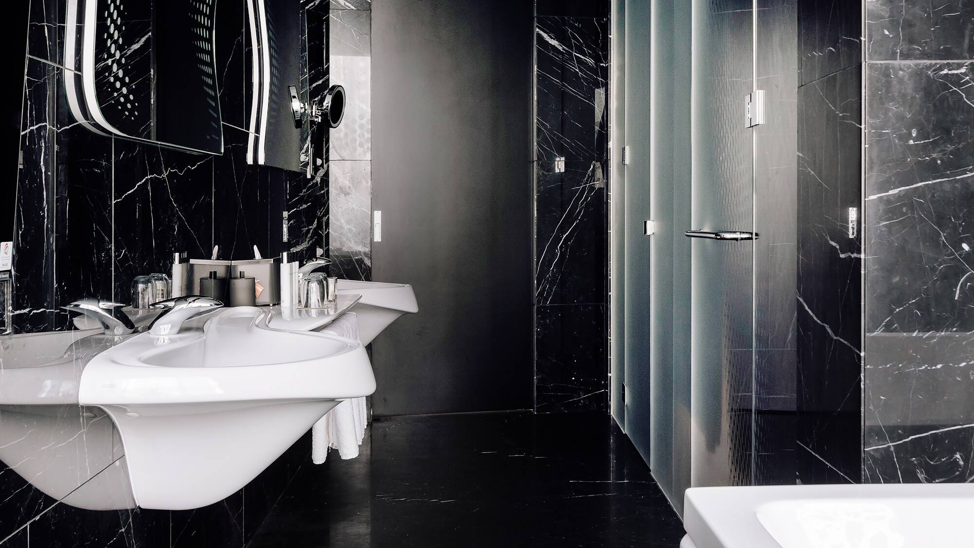 a bathroom with black marble walls and sinks