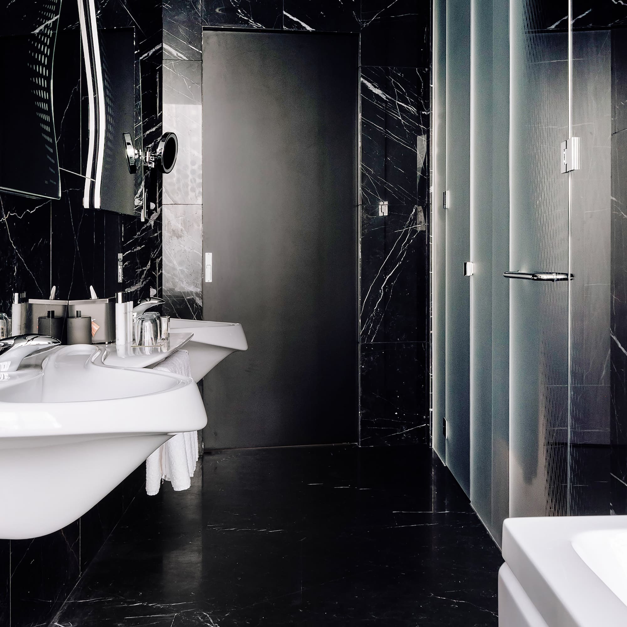 a bathroom with black marble walls and sinks