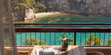 a table with a vase of sunglasses and a vase of flowers on a balcony overlooking a body of water