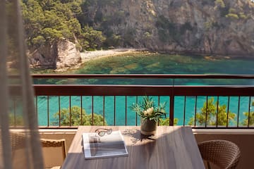 a table with a vase of sunglasses and a vase of flowers on a balcony overlooking a body of water