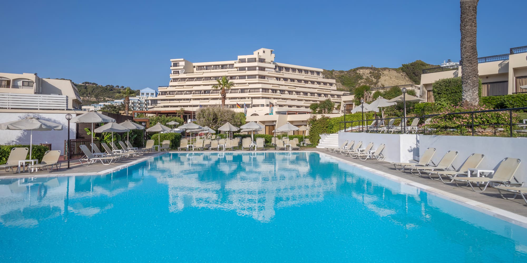 a pool with chairs and umbrellas in front of a building