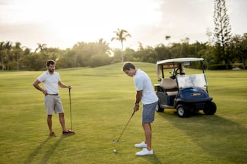 a man holding a golf club and another man standing on a golf cart