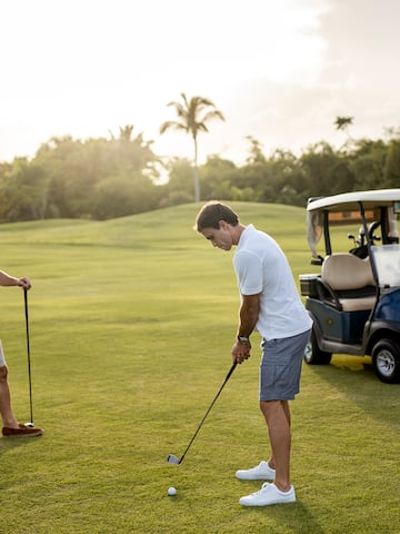 a man holding a golf club and another man standing on a golf cart